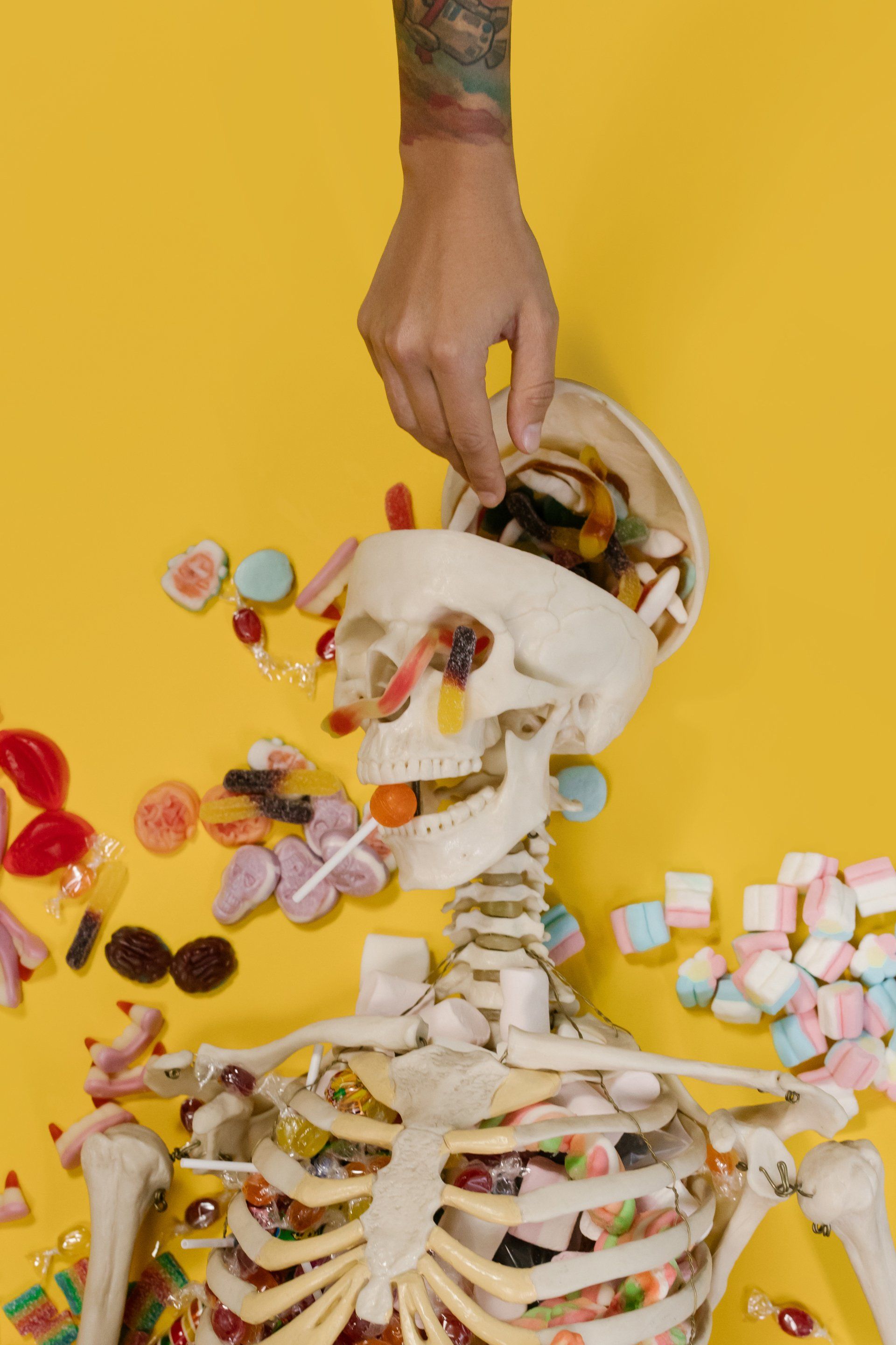 A person is putting candy into a skeleton 's mouth.