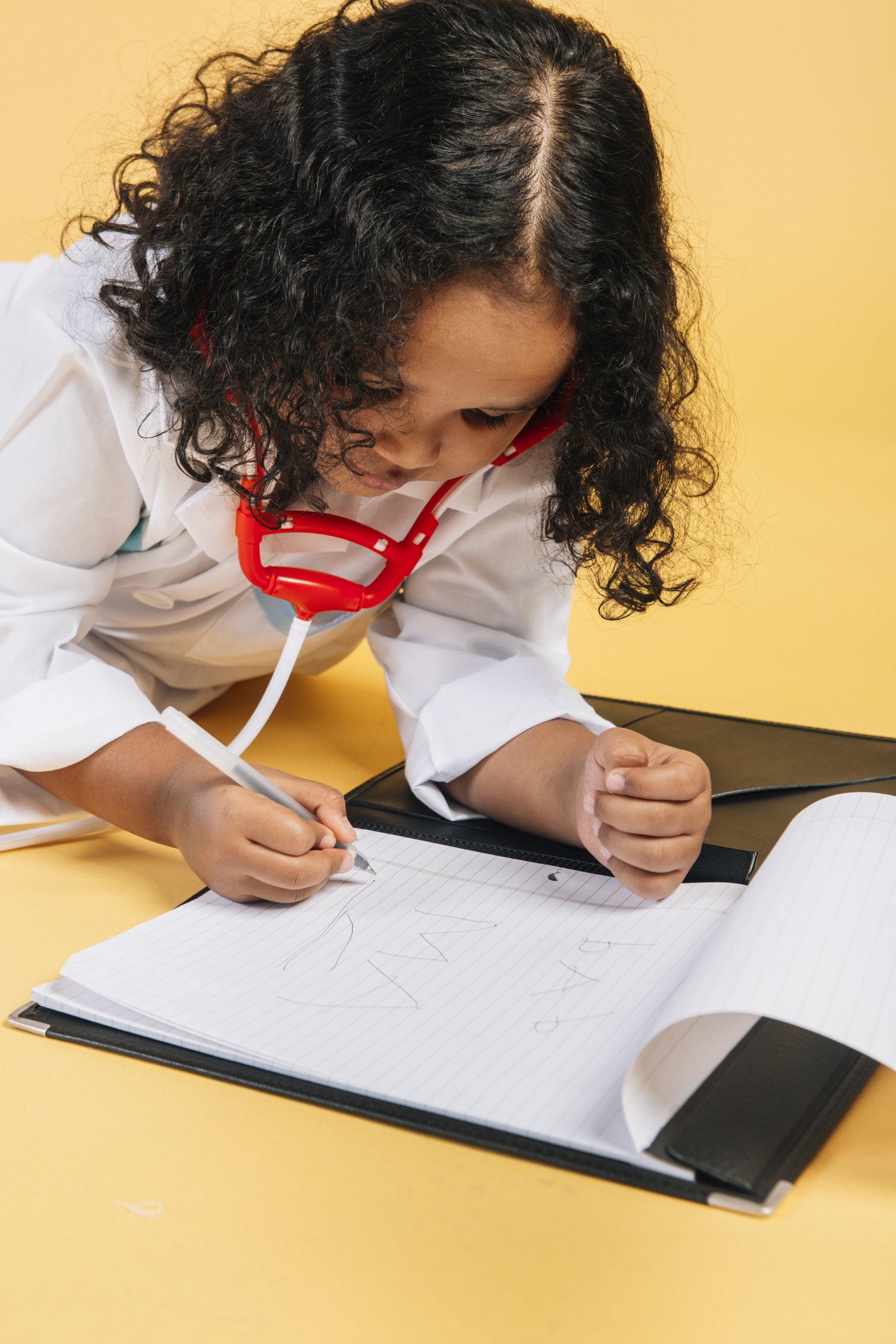Little girl pretending to be a pediatrician writing medical notes