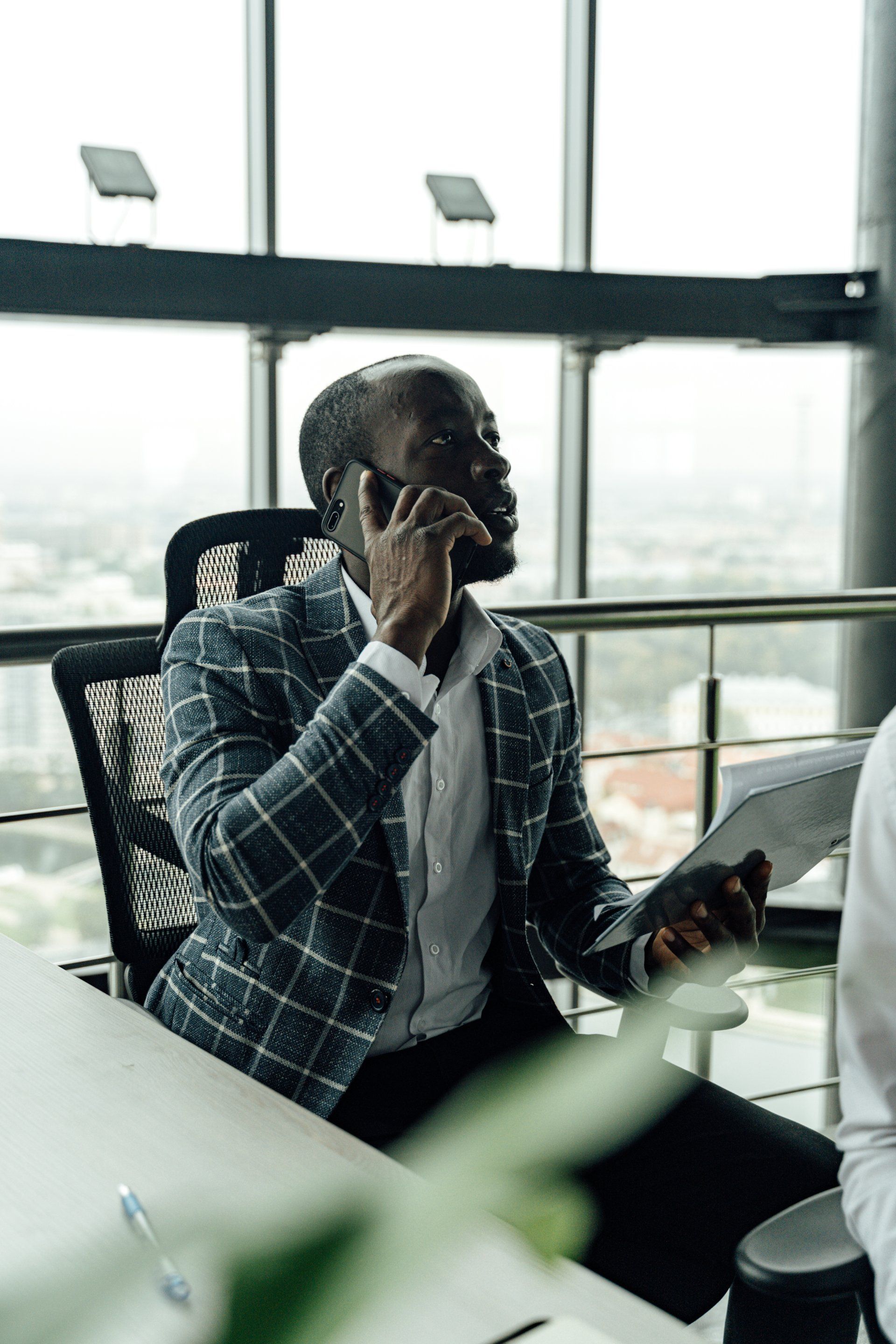 A man is sitting at a table talking on a cell phone.