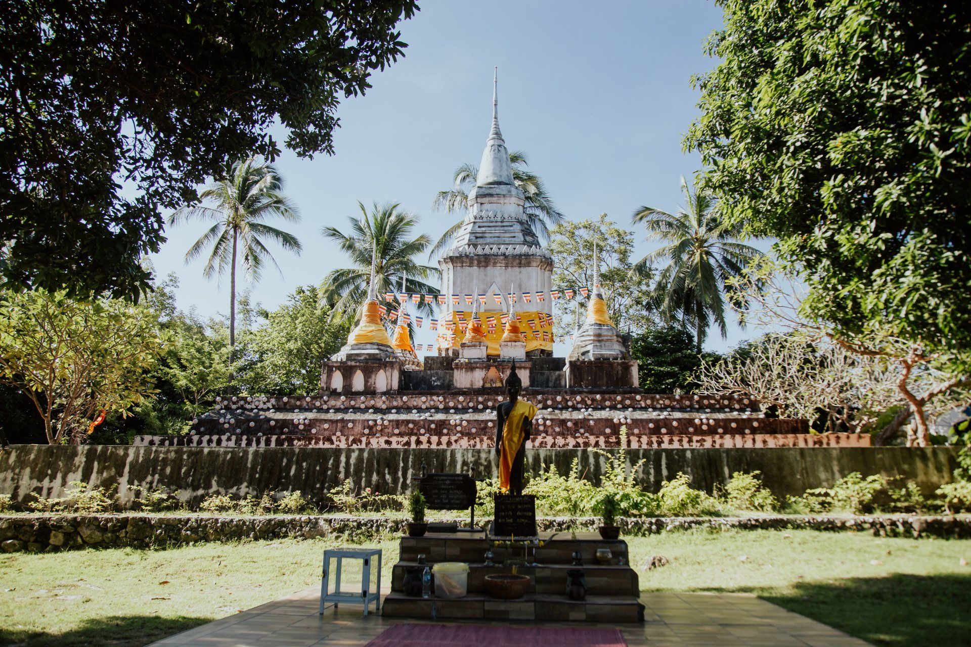 A temple with a statue in front of it surrounded by trees.