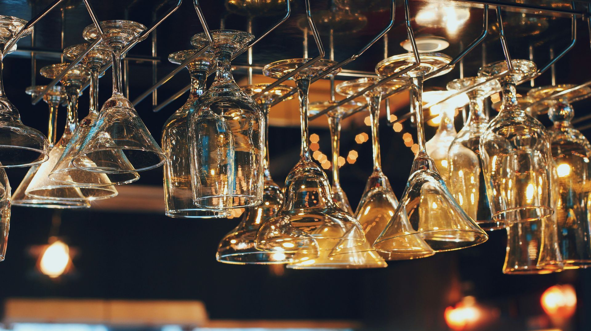 A bunch of wine glasses are hanging from a rack.