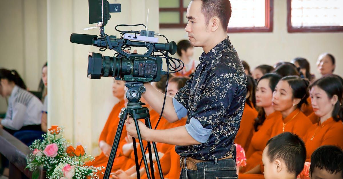 A man is holding a video camera in front of a group of people.
