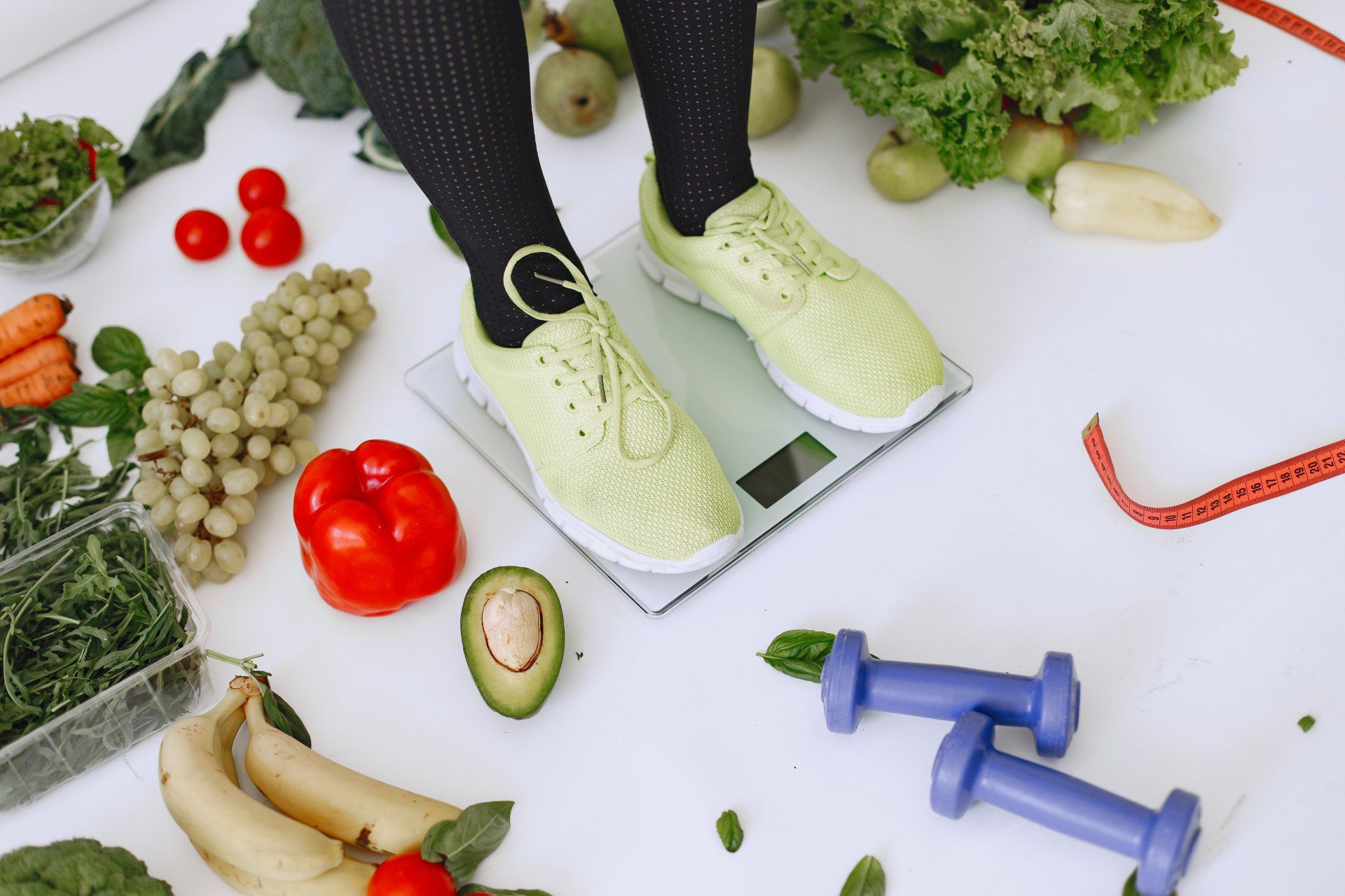 A person is standing on a scale surrounded by fruits and vegetables.