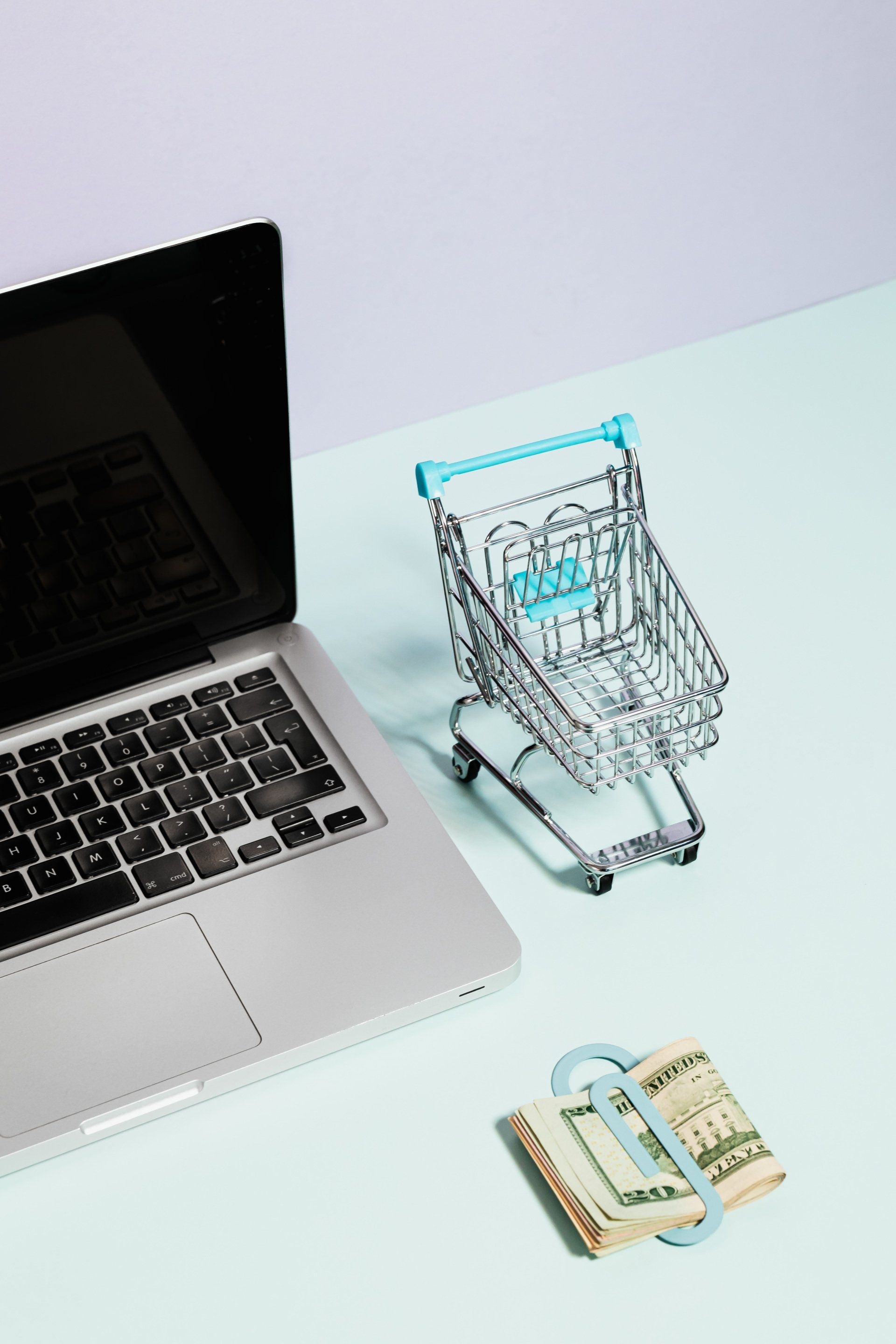A small shopping cart sits next to a laptop