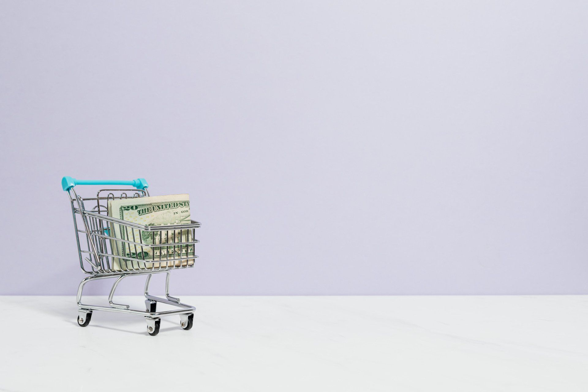 A small shopping cart with cash inside on a white background
