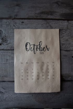 A calendar for october is sitting on a wooden table.