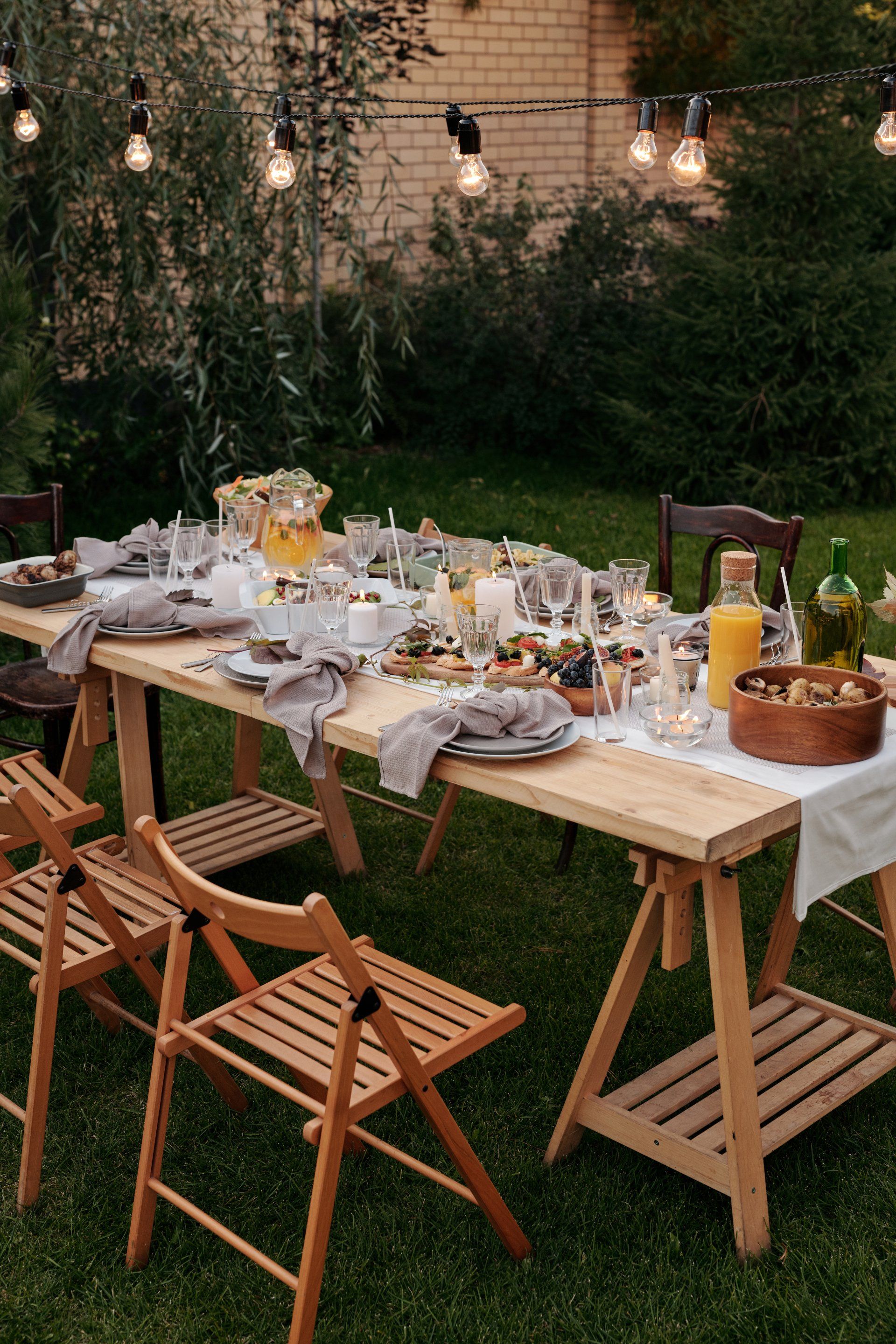 A wooden table with a lot of food on it is sitting on top of a lush green lawn.