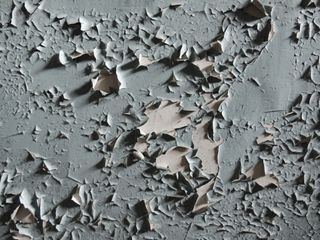 A close up of a gray wall with peeling paint