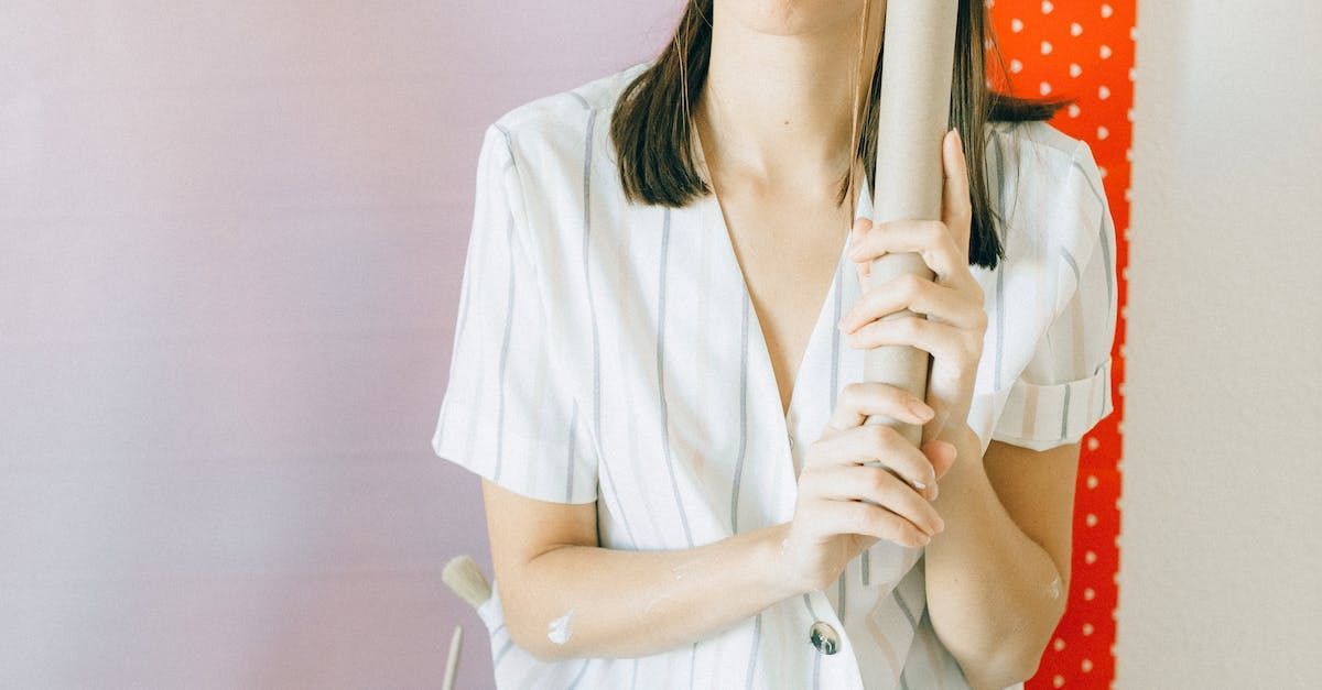 A picture of a woman holding a roll of wallpaper