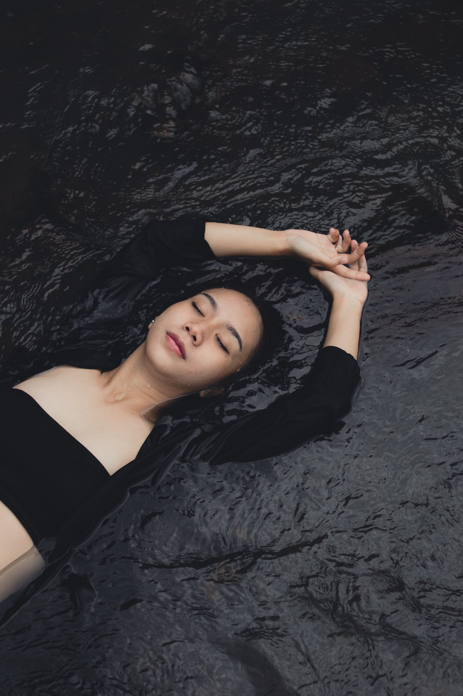 A woman is laying on a black blanket with her eyes closed.