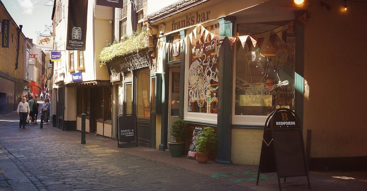 A group of people are walking down a cobblestone street in front of a store.