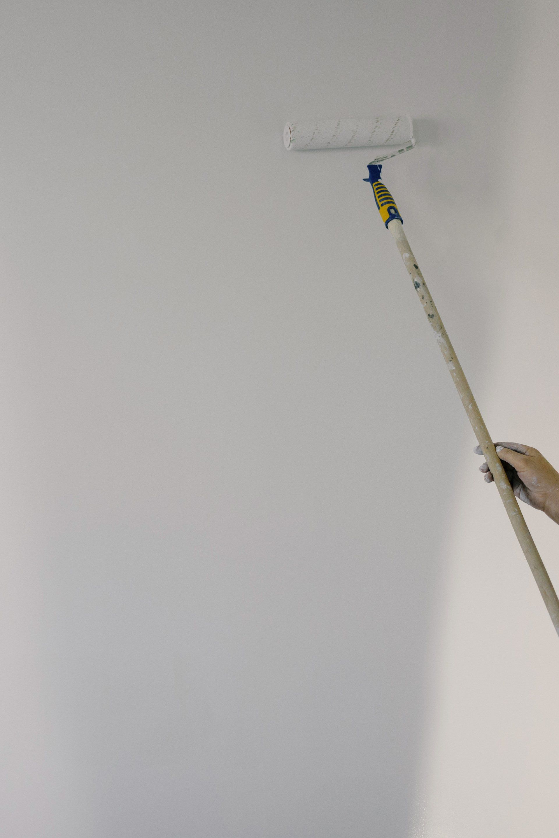 A person is painting a wall with a paint roller.