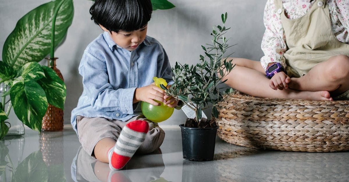 Two children watering indoor plants together on the floor