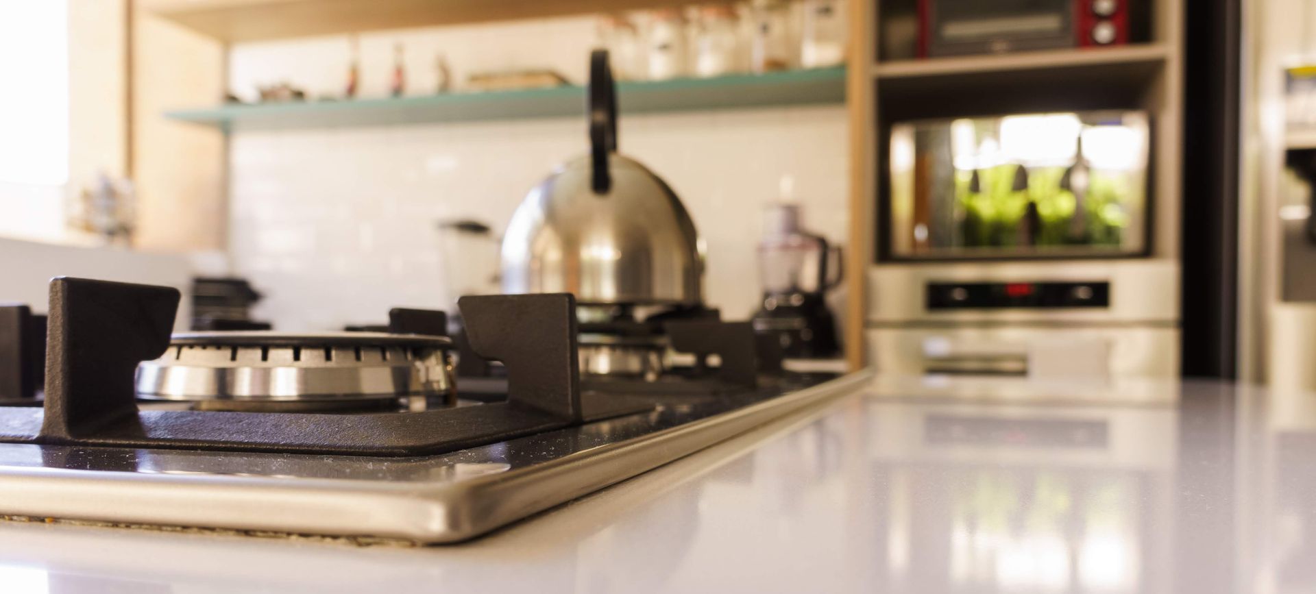 A kitchen with a stove top oven and a kettle on it.