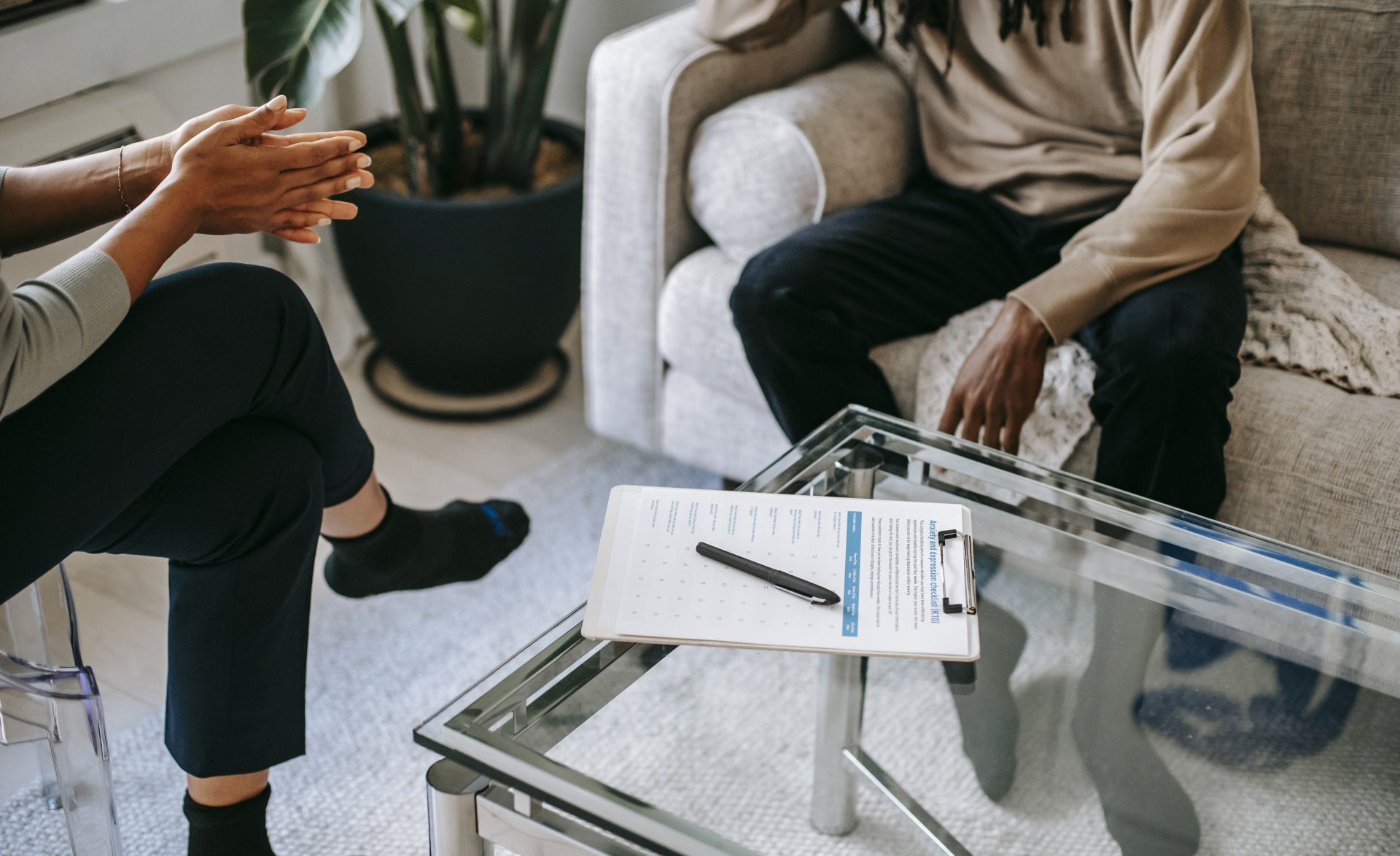 A man and a woman are sitting on a couch talking to each other.