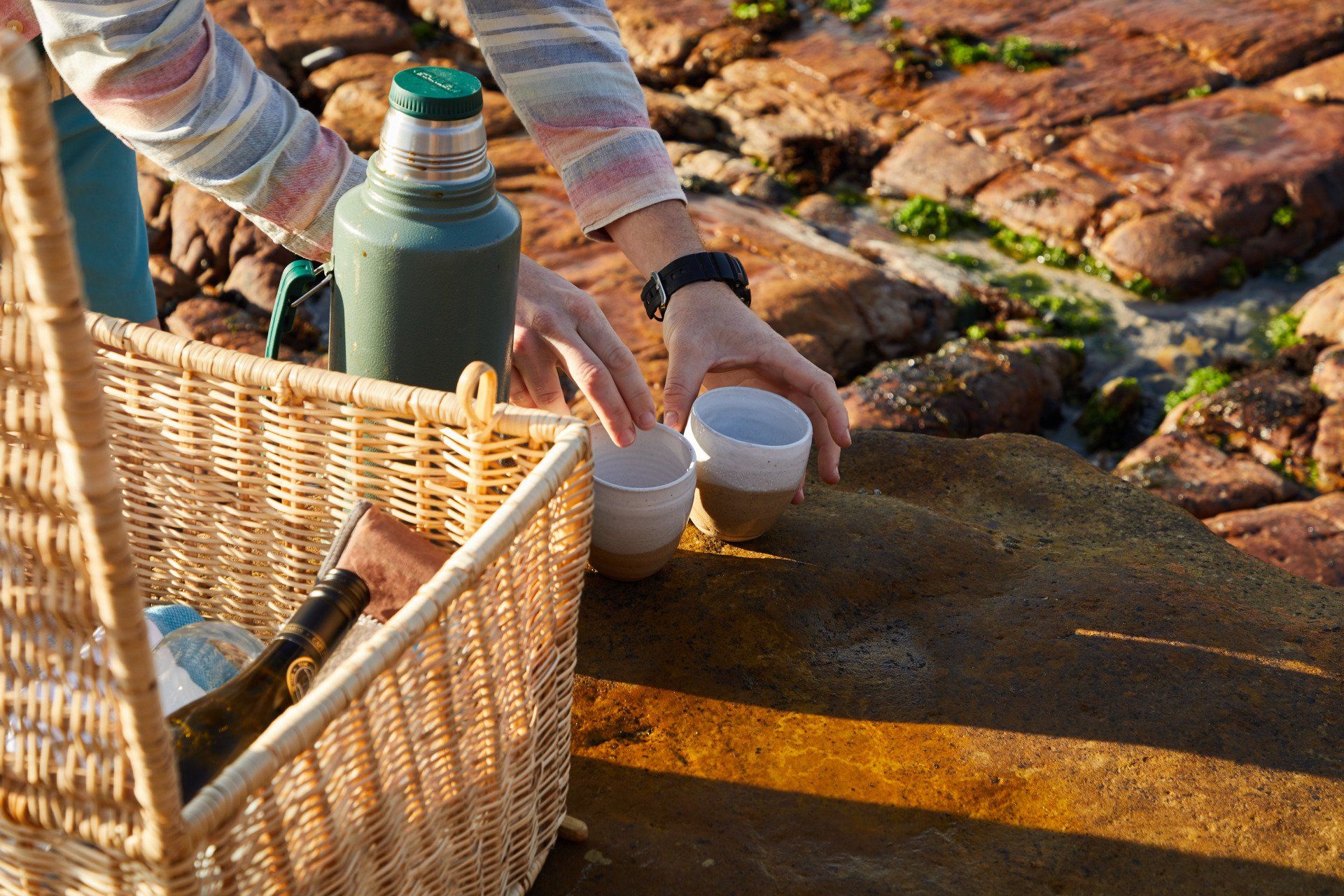 Eine Person gießt etwas aus einer Flasche in eine Tasse