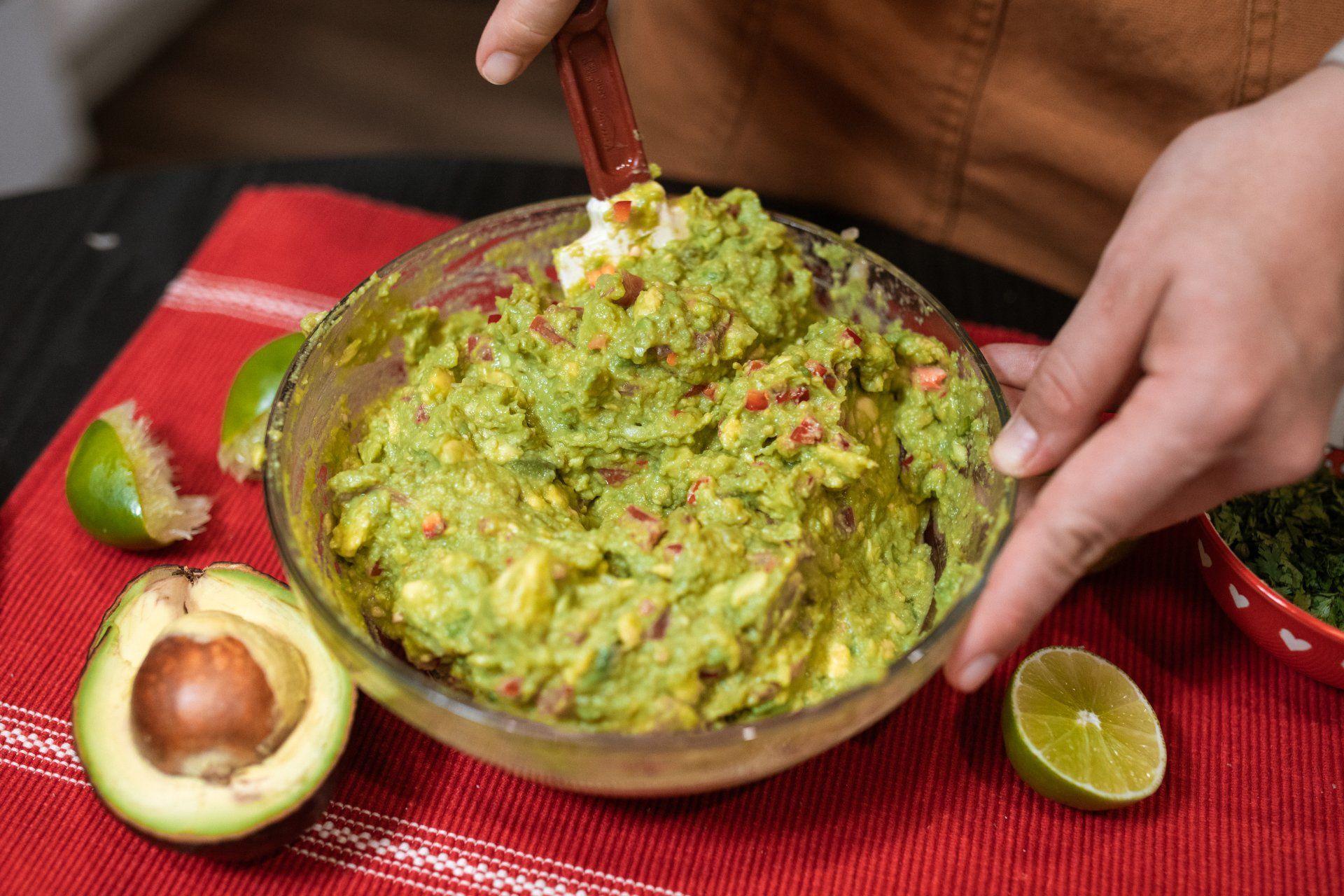 A person is mixing guacamole in a bowl with a spoon.