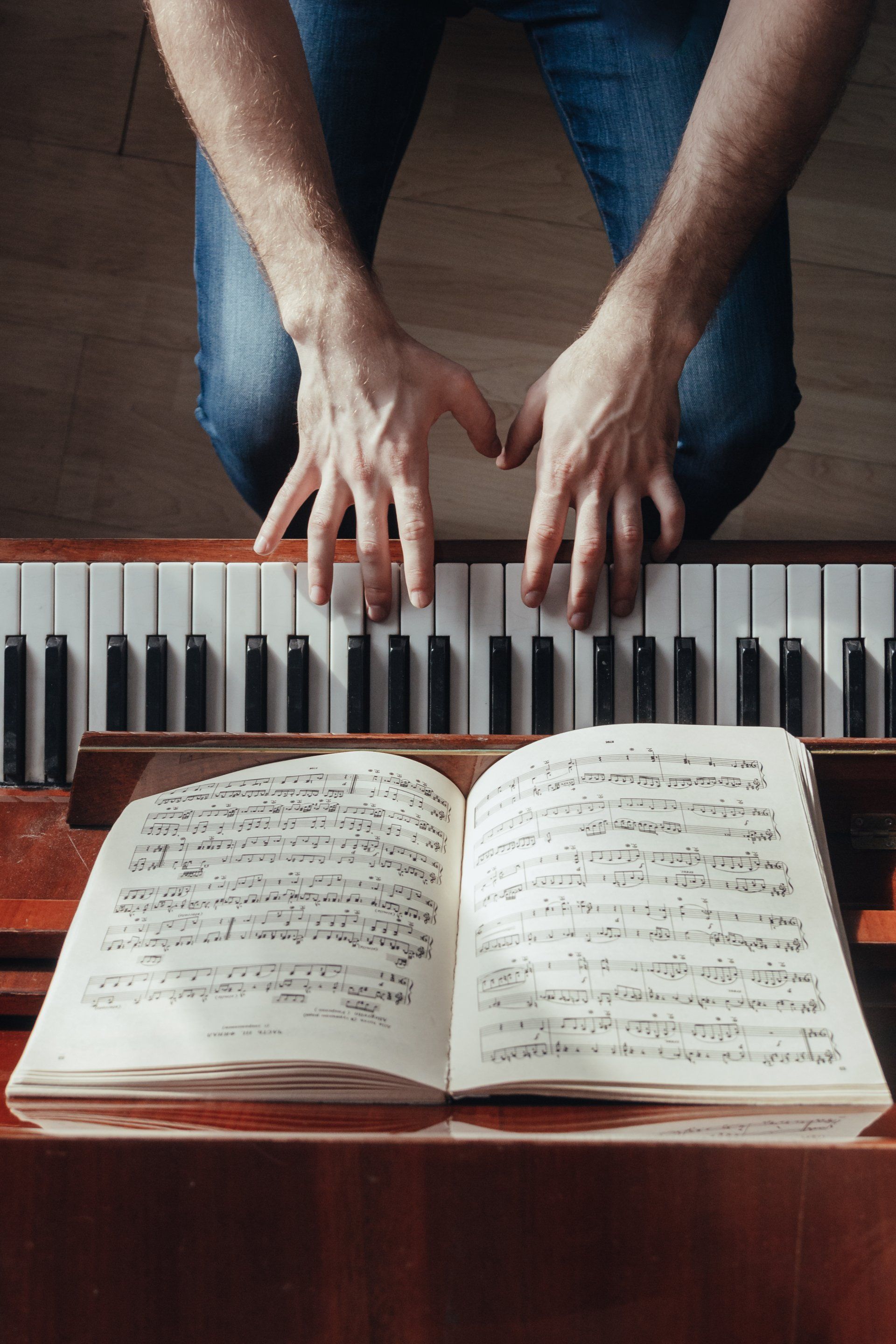 A person playing a piano with sheet music open in front of them.