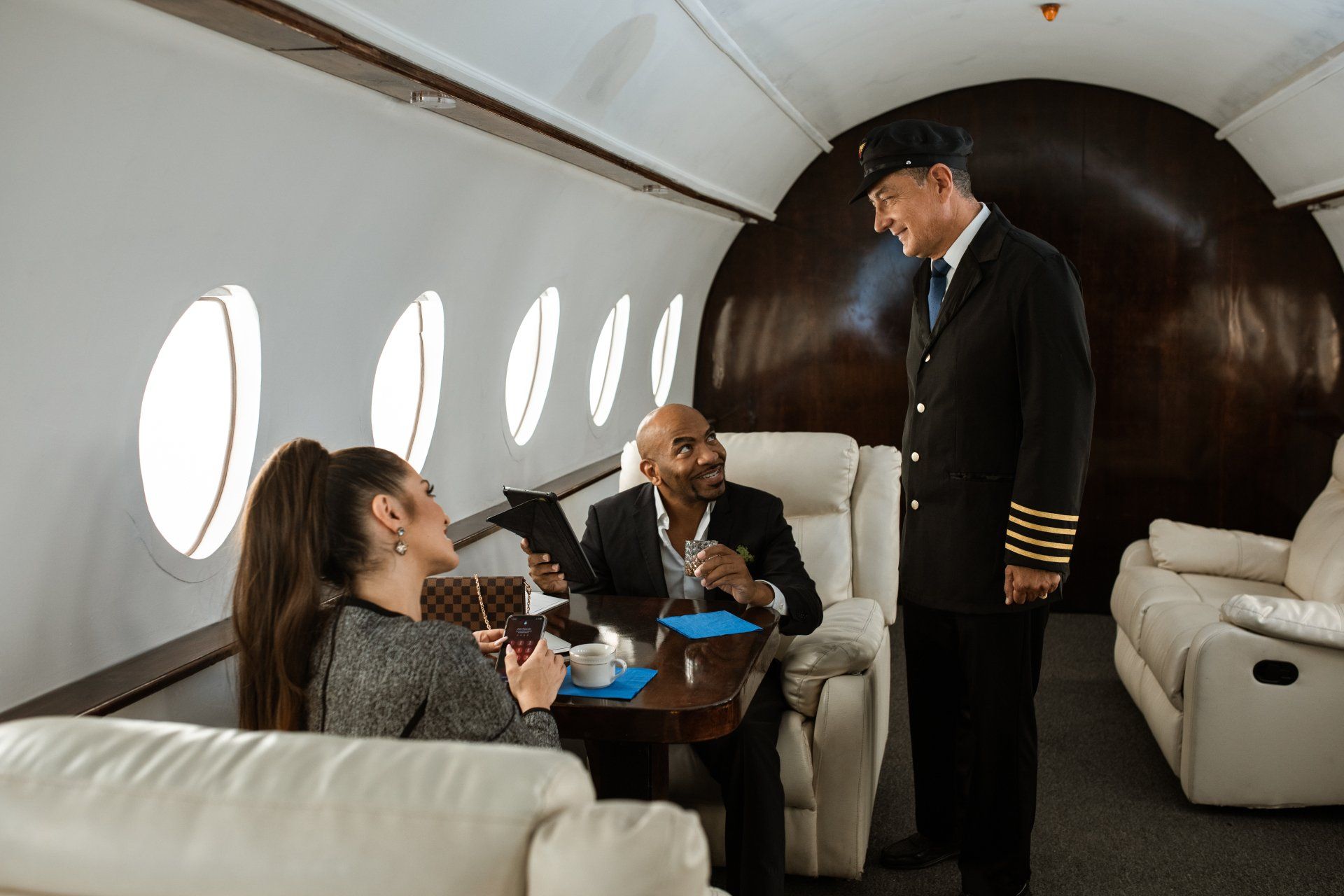 A pilot is talking to two people on a private jet.