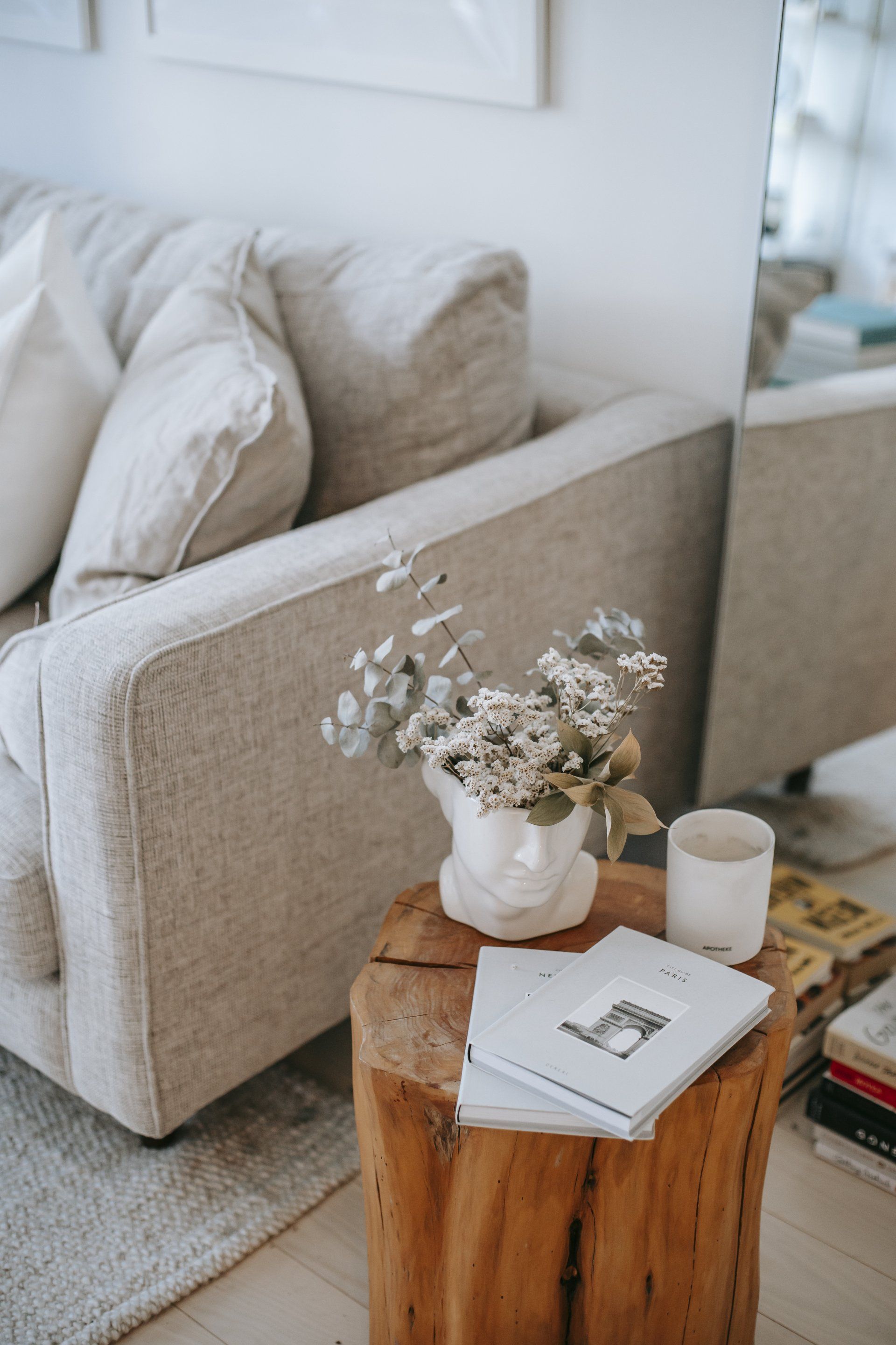 A vase of flowers is sitting on a wooden stump next to a couch.