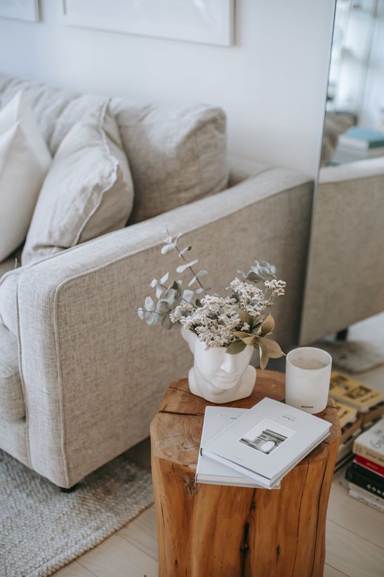 A living room with a couch and a wooden table with a vase of flowers on it.