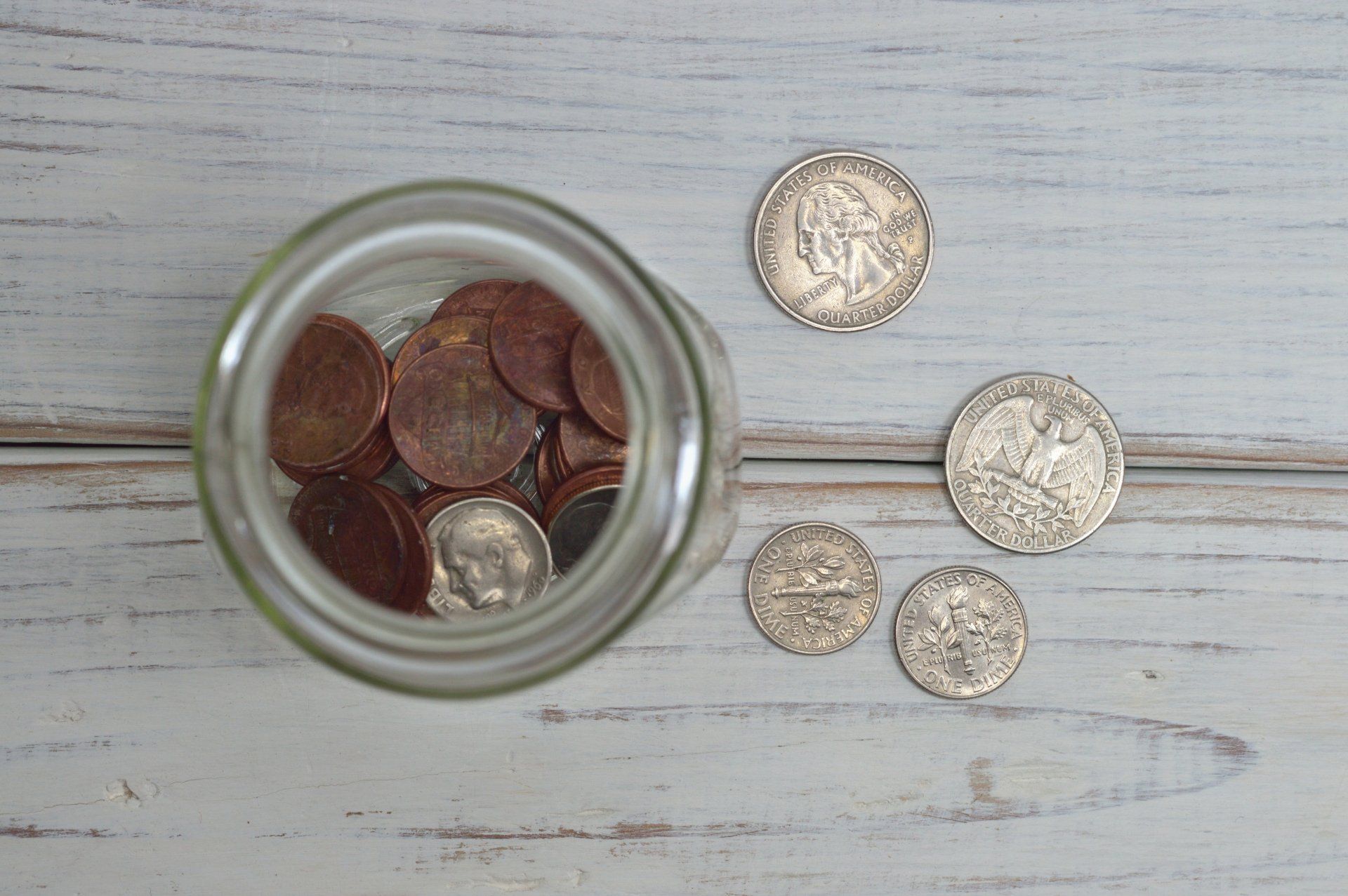 a glass jar filled with coins on a wooden table .