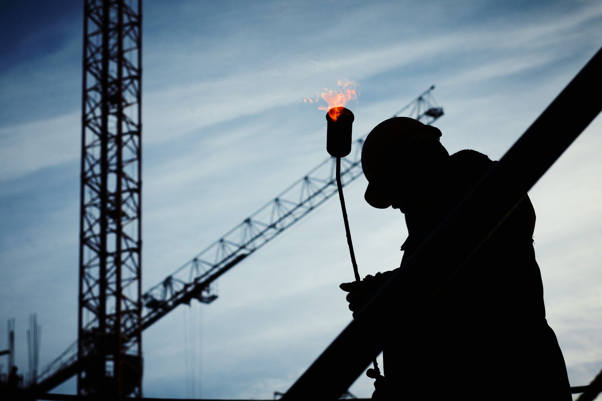 Una silueta de un hombre sosteniendo una antorcha en un sitio de construcción.