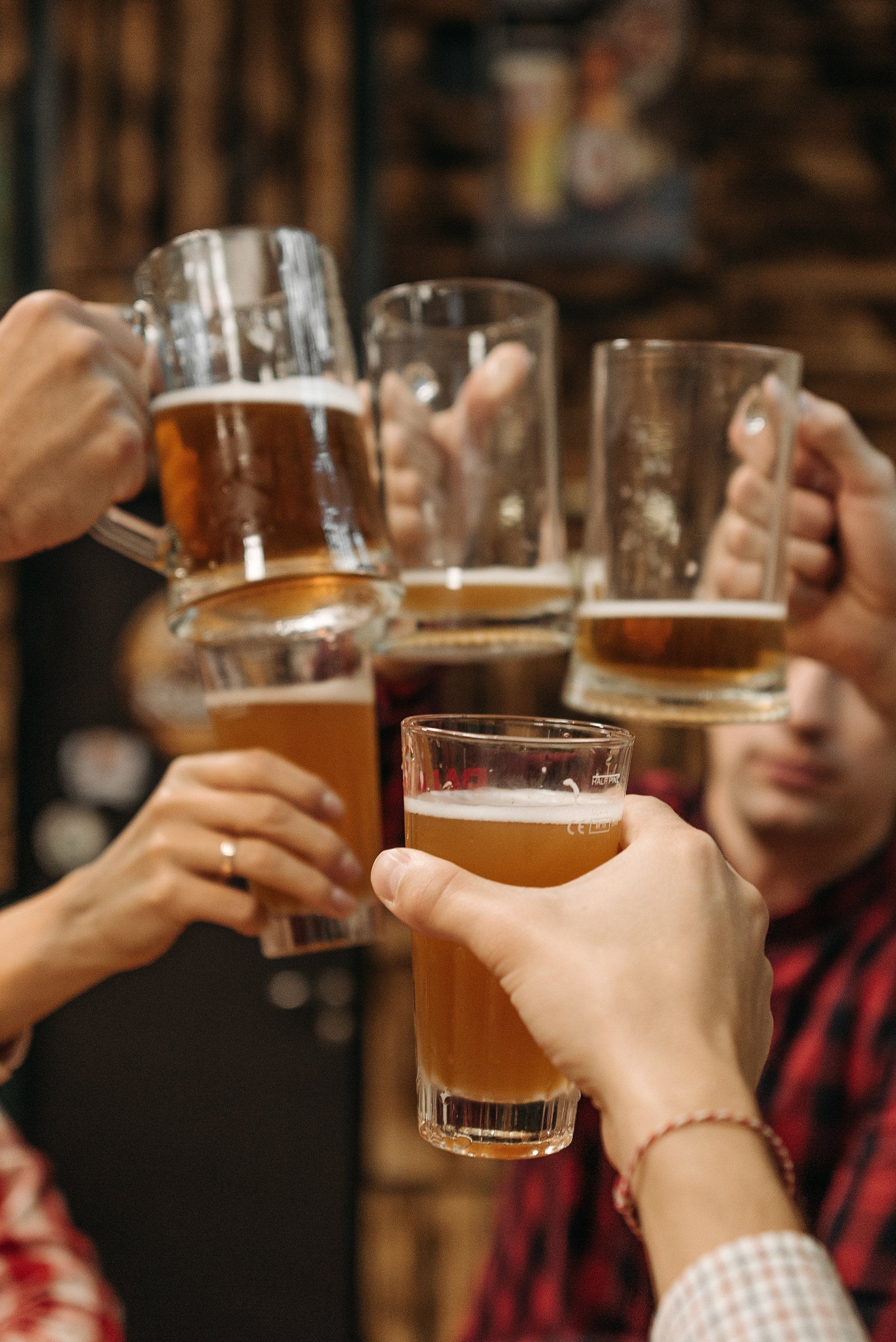 a group of people are toasting with beer mugs .