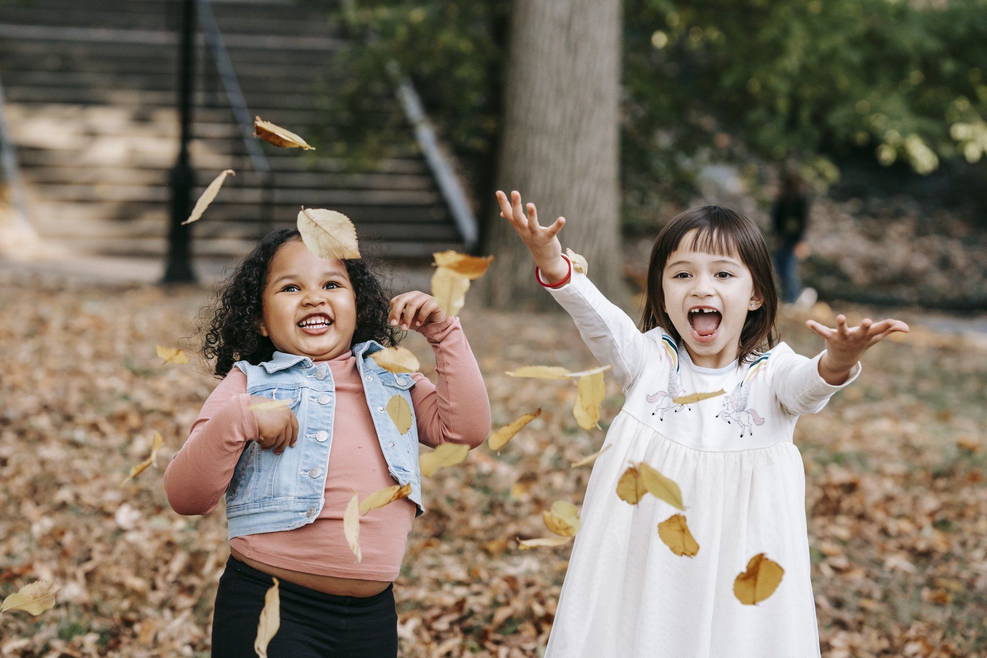 Two girls are playing in the leaves