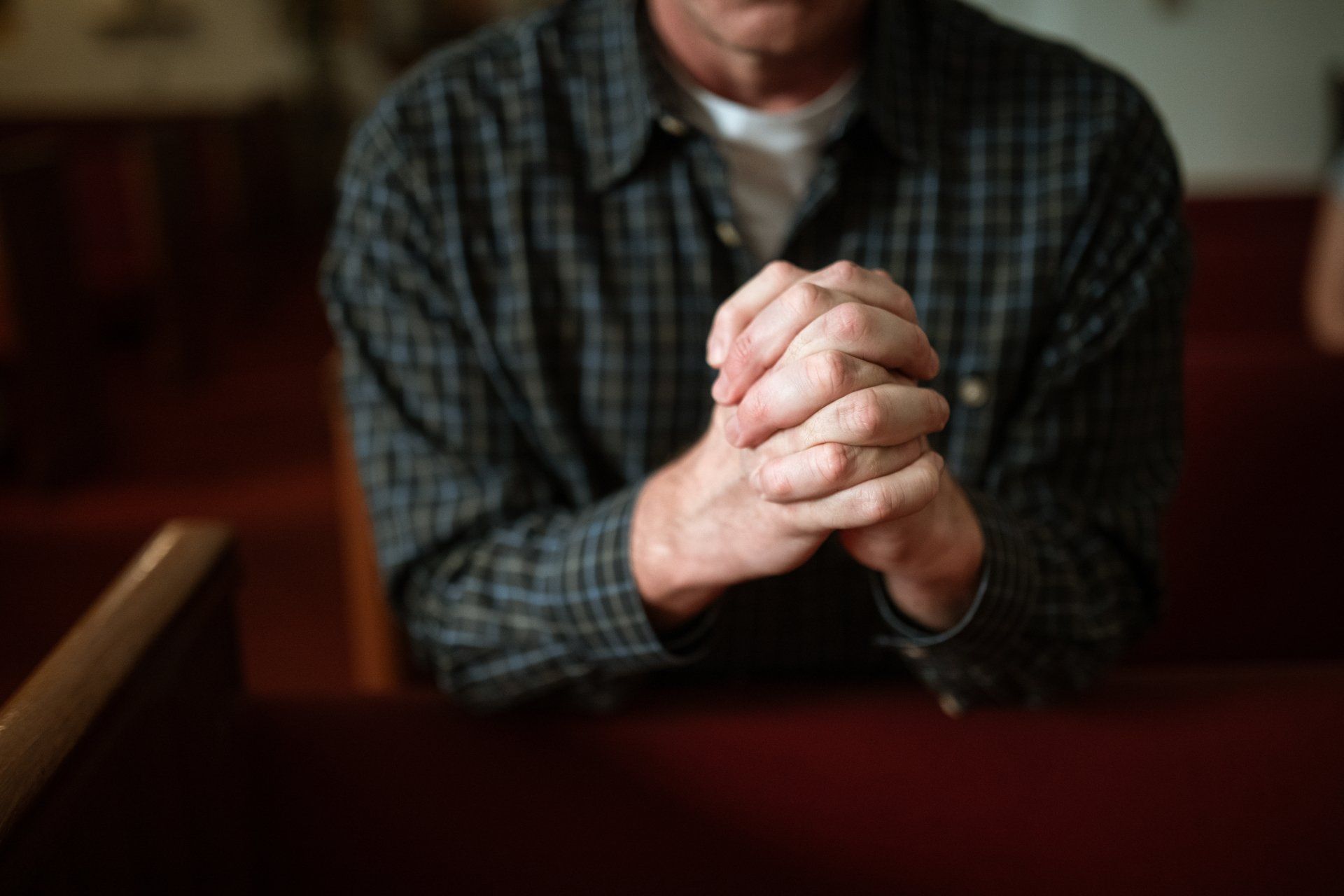 A man prays in a church pew