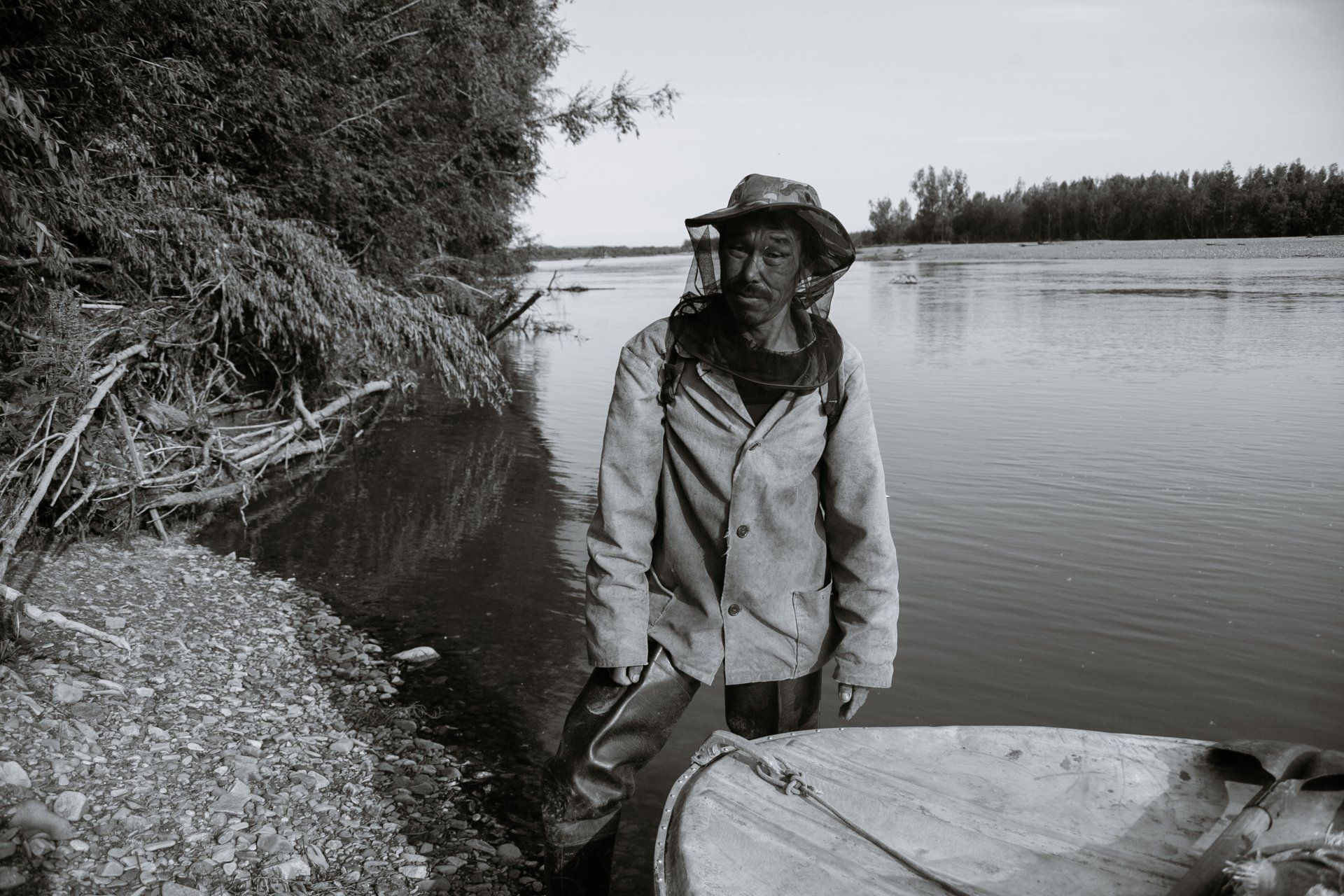 A man in a hat is standing next to a boat in the water.