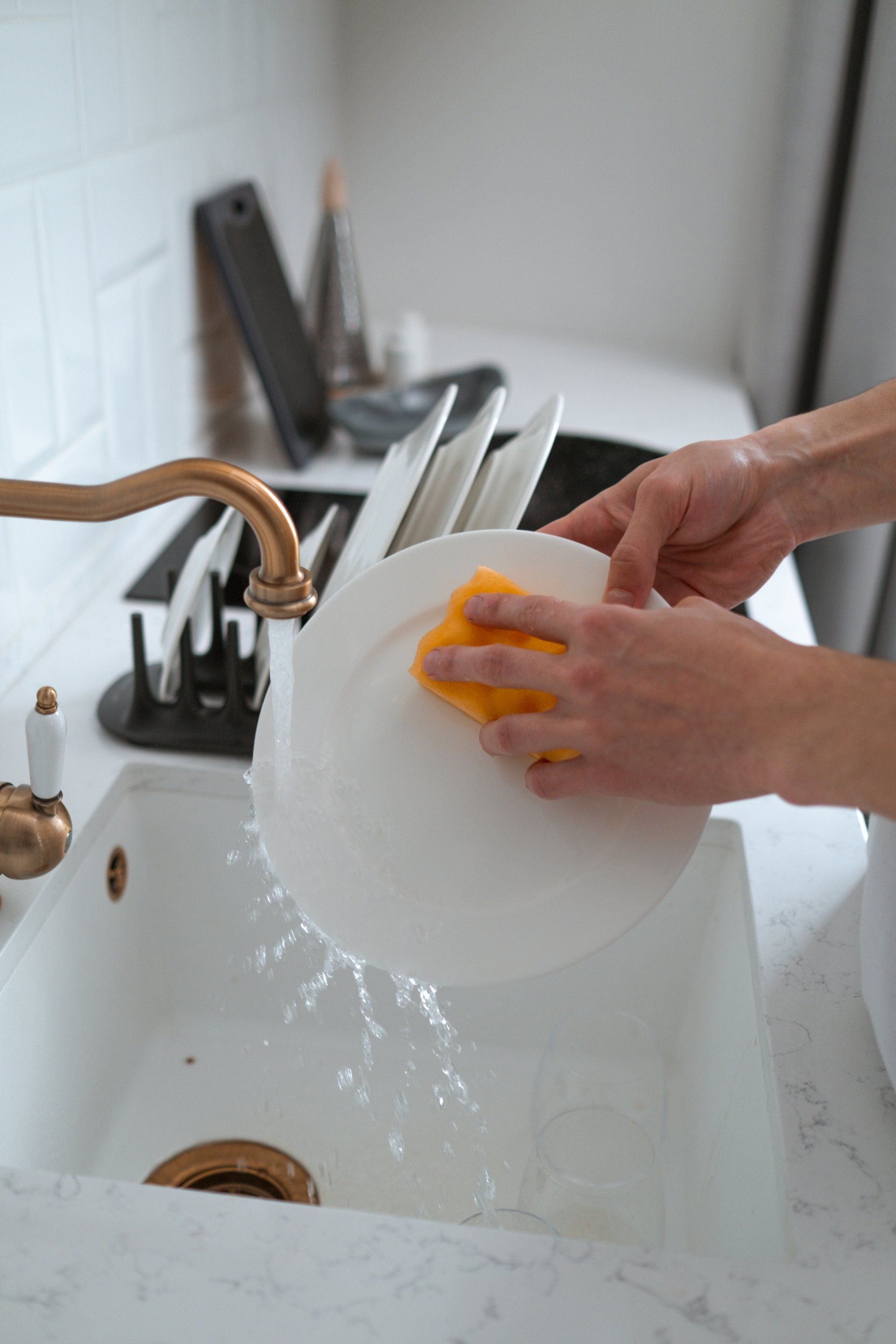 a person is washing a plate in a kitchen sink with a sponge .