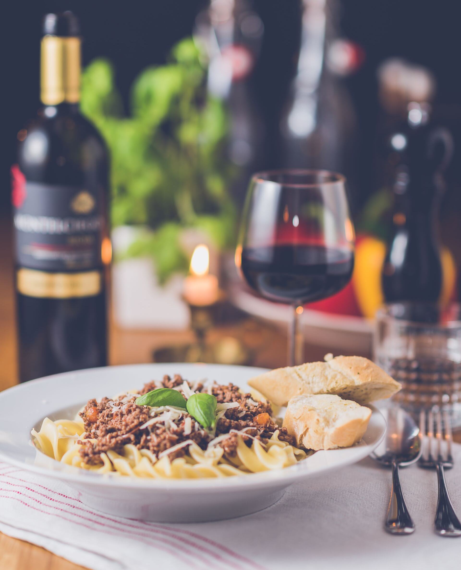 A plate of food with a bottle of wine in the background