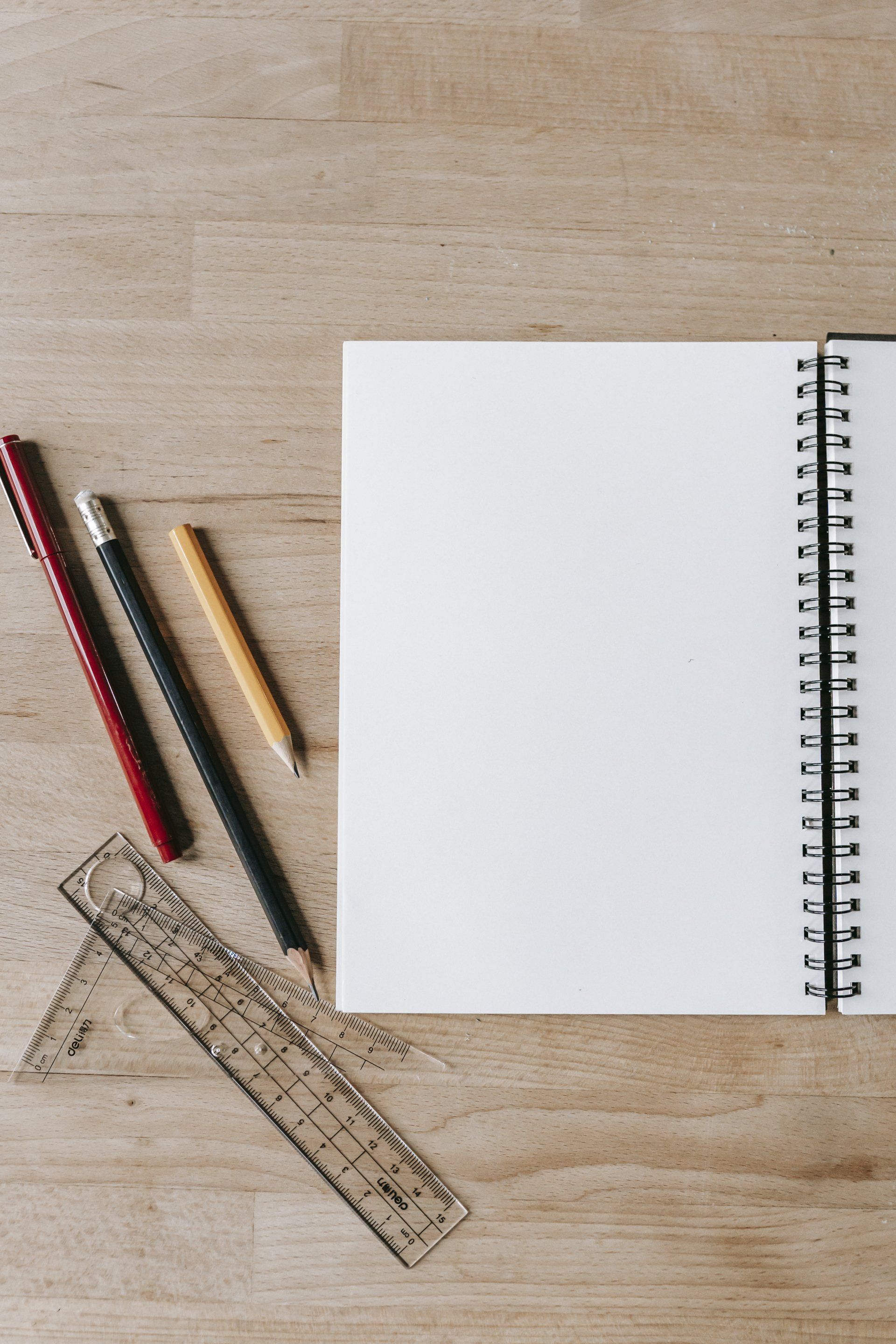 A notebook with pencils and a ruler on a wooden table