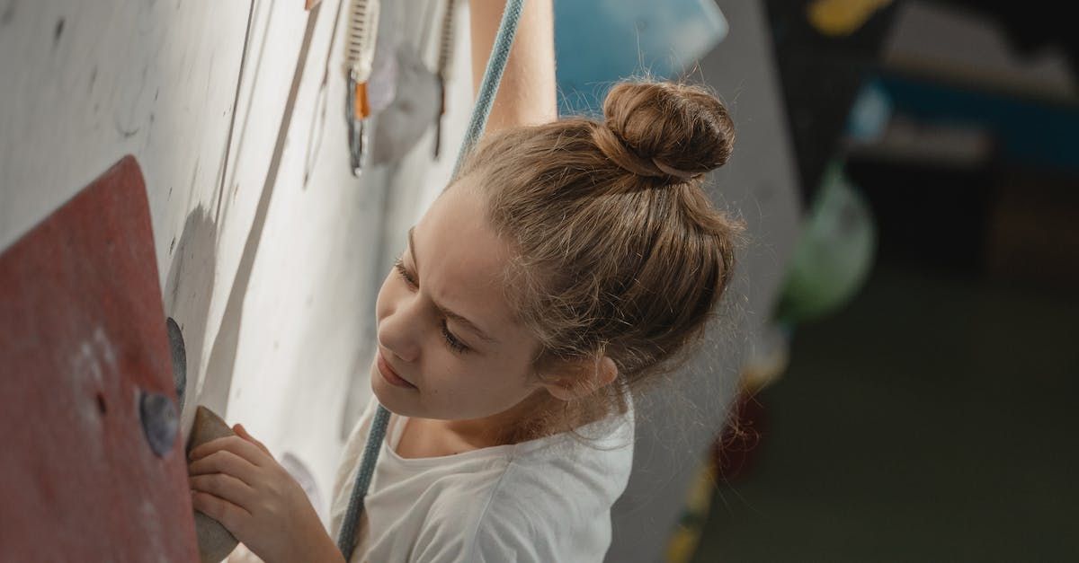 A young girl is climbing a climbing wall.