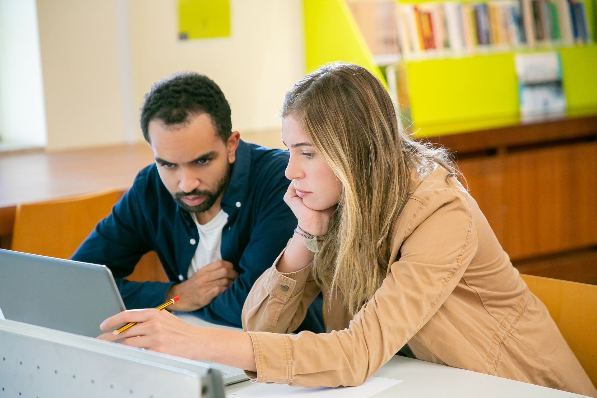 A man and a woman are looking at a laptop computer.