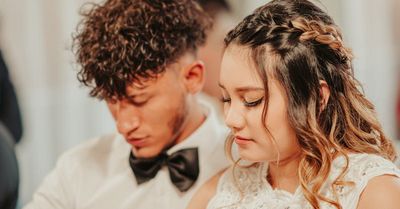 A bride and groom are sitting next to each other at a wedding reception.