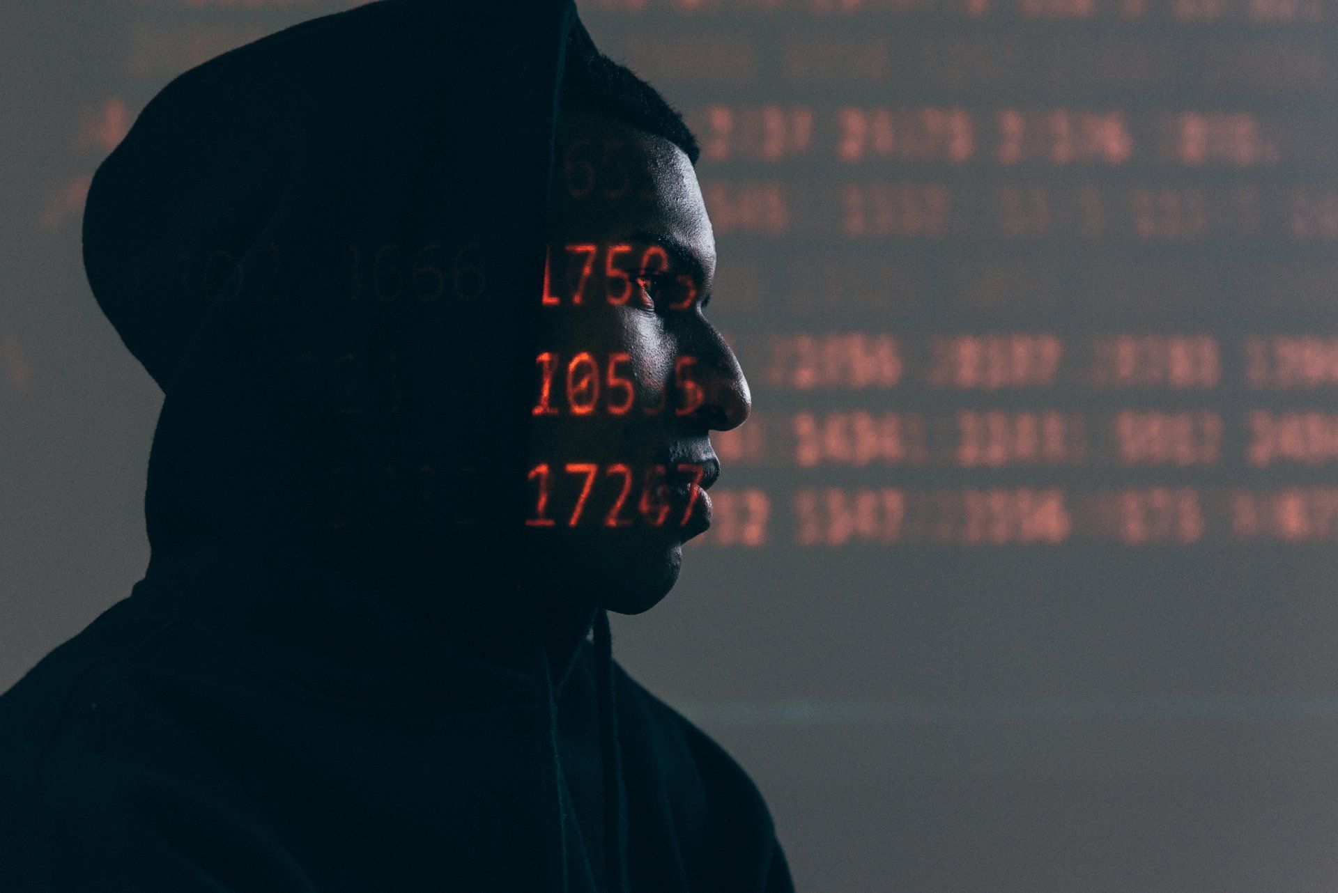 Silhouette of a person with data projected on their face. Dark setting, looking to the side. Red data overlay.
