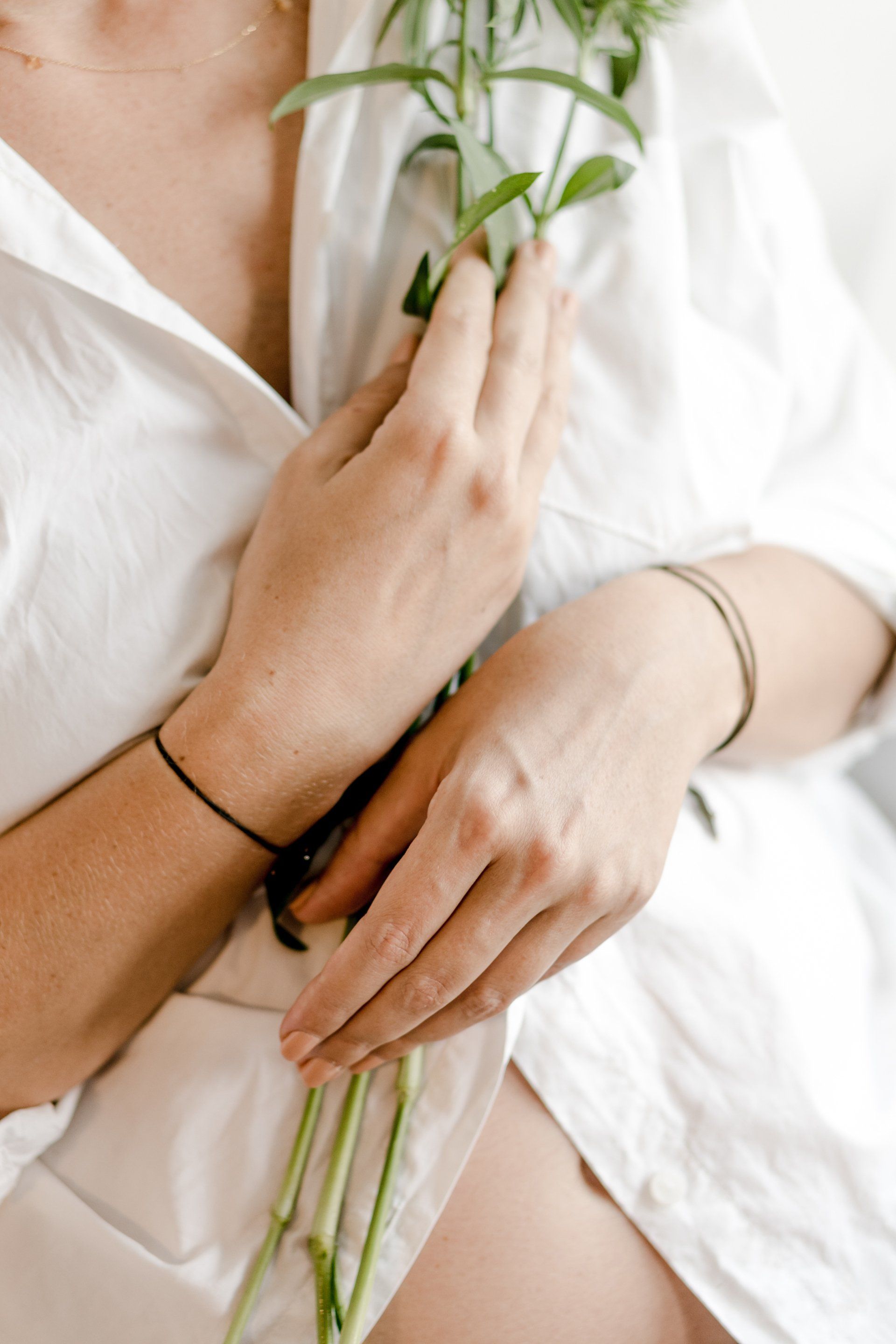 Woman in a white shirt holding a sprig of greenery