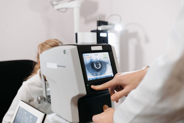 Una persona utilizza un apparecchio per l'esame della vista mentre un'altra indica il display.