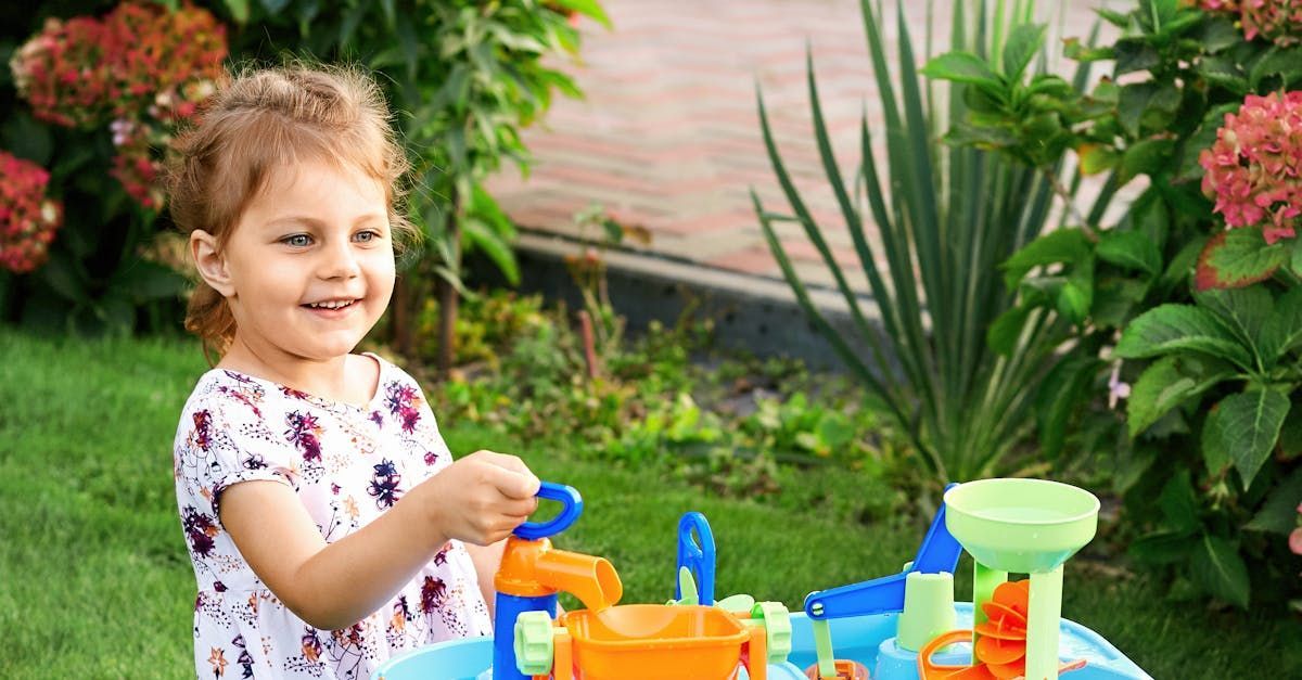 A little girl is playing with a water toy in the garden.