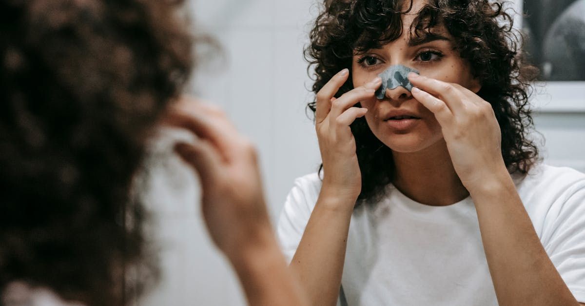 a woman is caring her nose in front of a mirror after getting a nose job.