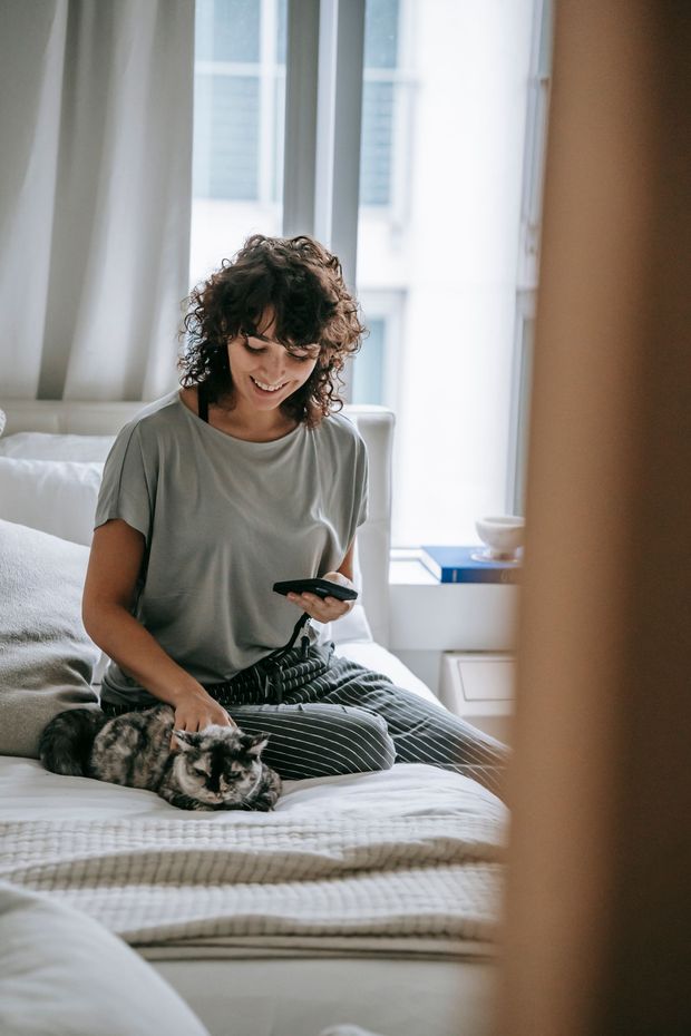 A woman is sitting on a bed looking at her phone.