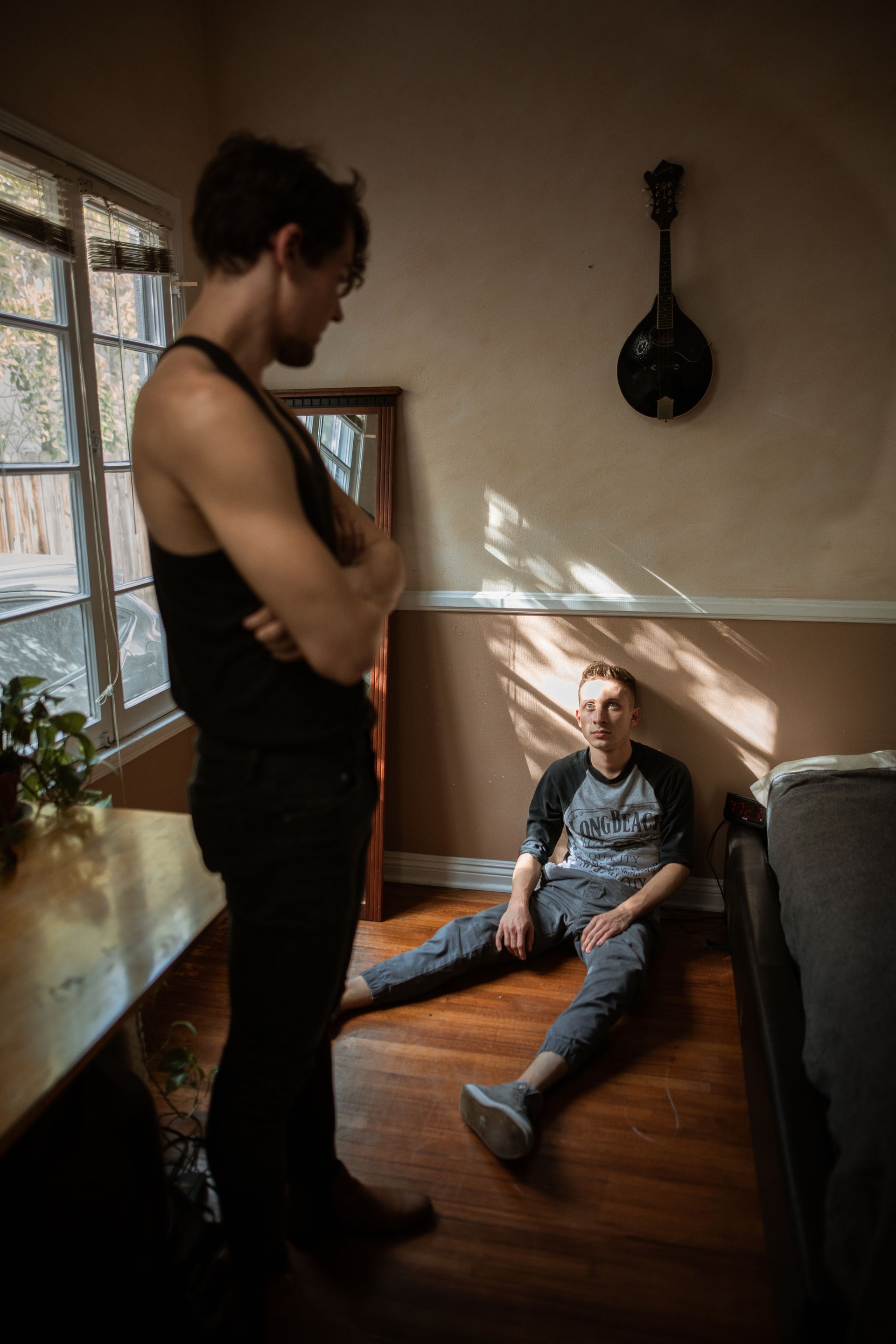 a young man sits on the floor looking up at his oppressor