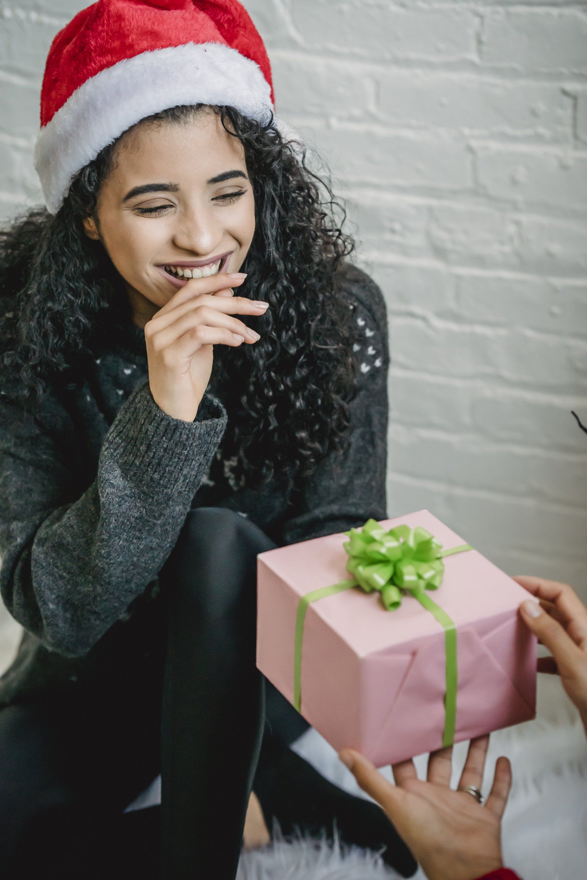 Girl wearing santa hat holding pink present with green bow Fusion Partners Central Coast