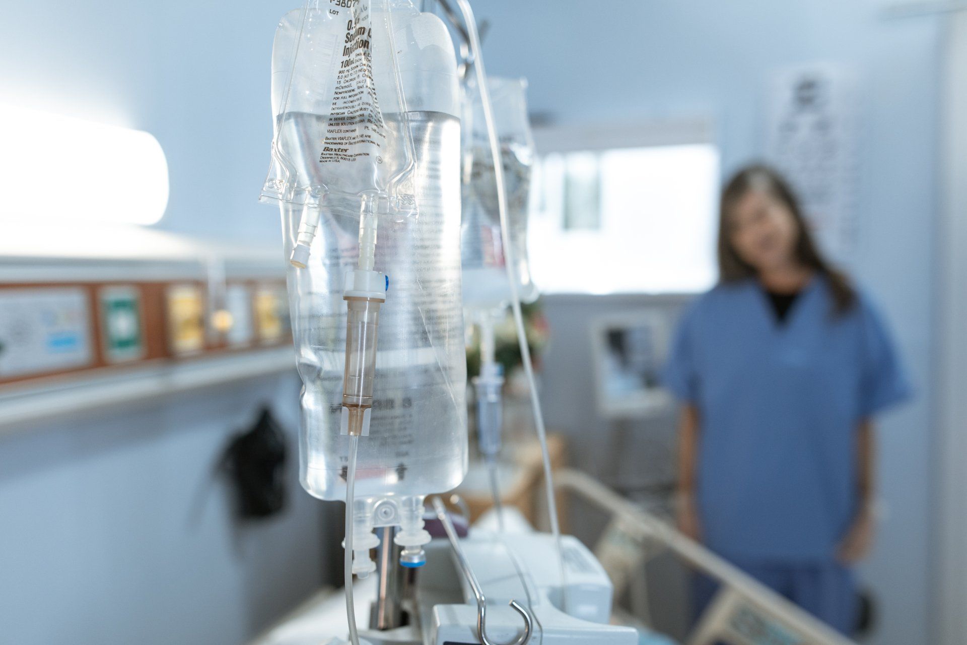a nurse is standing in a hospital room with a drip hanging from a machine .