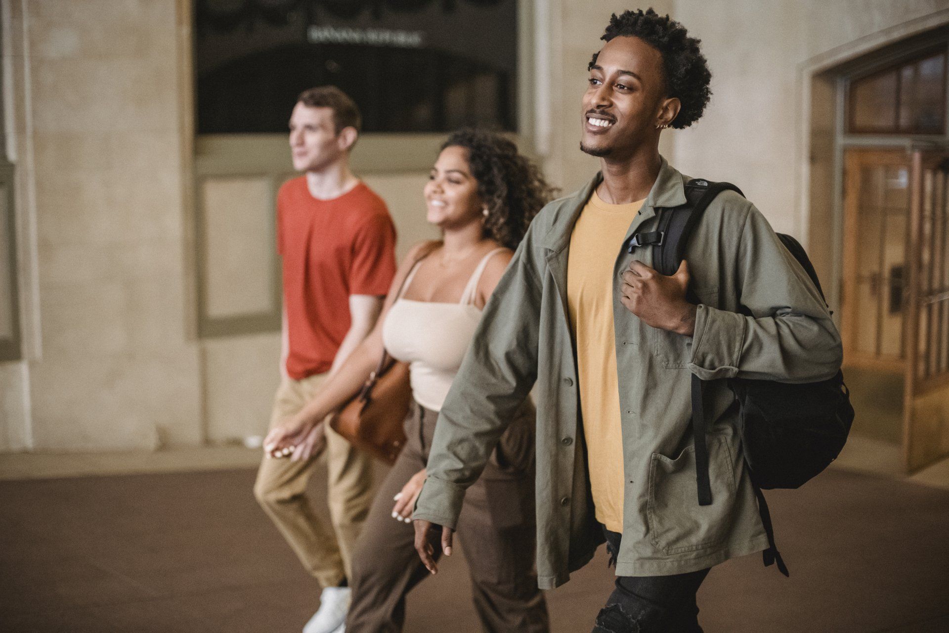 Three people walking together at night in a city street, smiling and chatting.