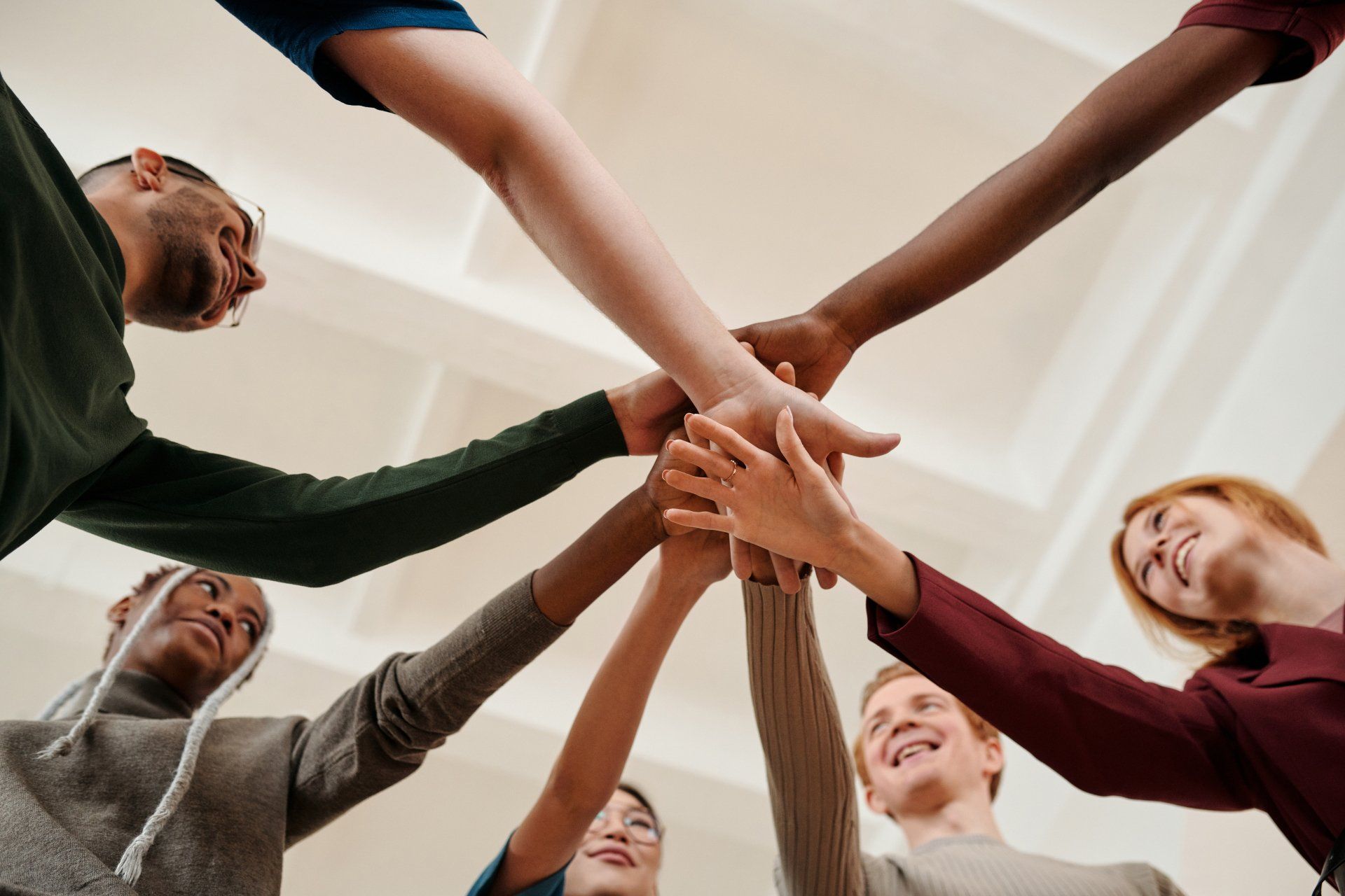 Hands of diverse people in a circle, symbolizing teamwork.