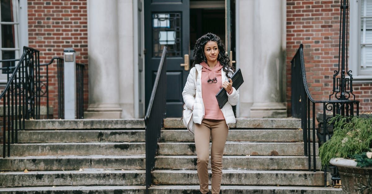 A woman is walking down the stairs of a building.