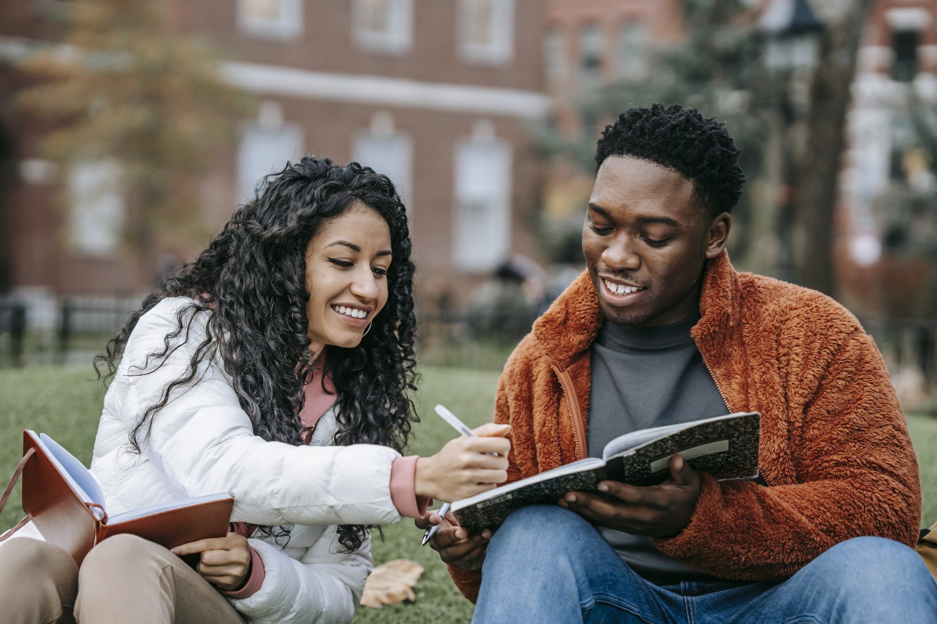 a man and a woman sit on the grass reading books